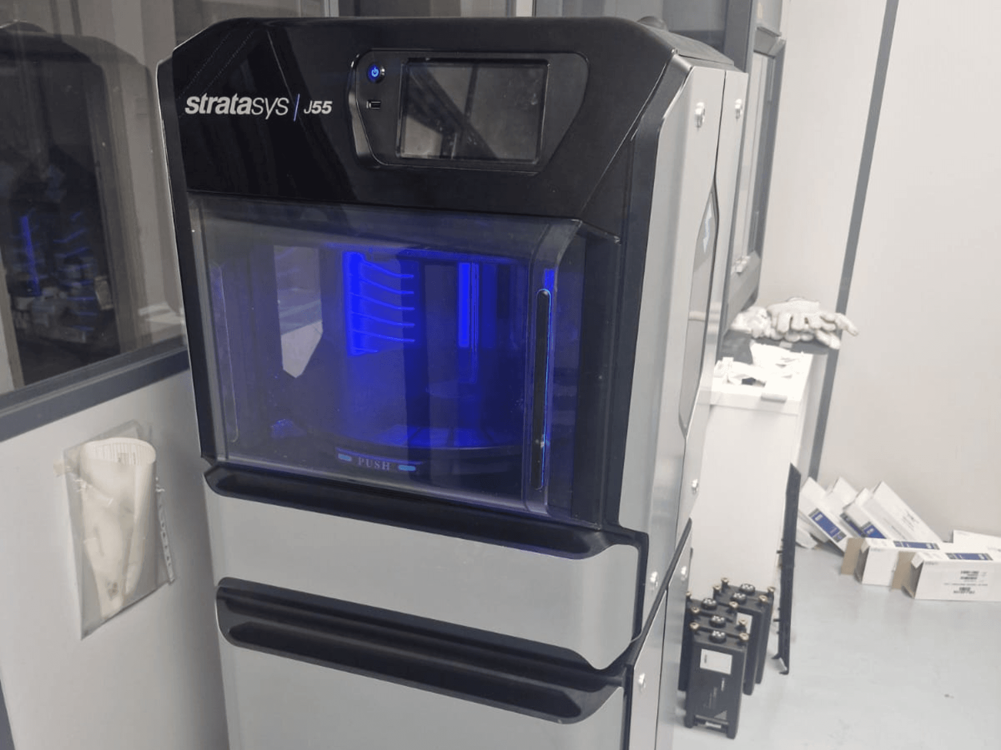 Stratasys J55 Prime plastikust 3D-printer külgvaates, mis näitab selle elegantset disaini ja valgustatud printimisala.