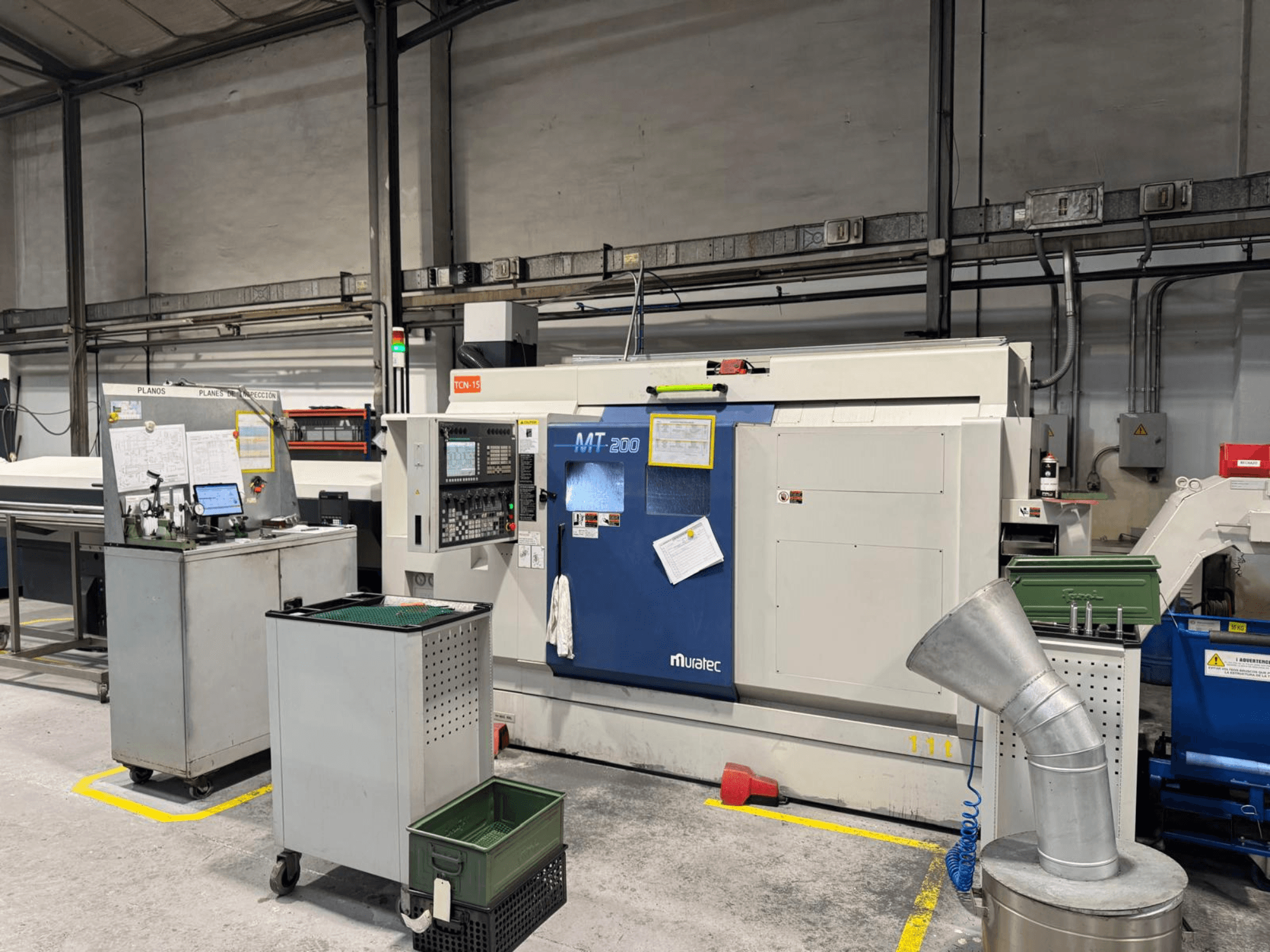 Muratec MT200 mitmevõlli treipink tehase seadistuses, vaadatuna eestpoolt, koos juhtpaneeli ja ümbritsevate seadmetega.