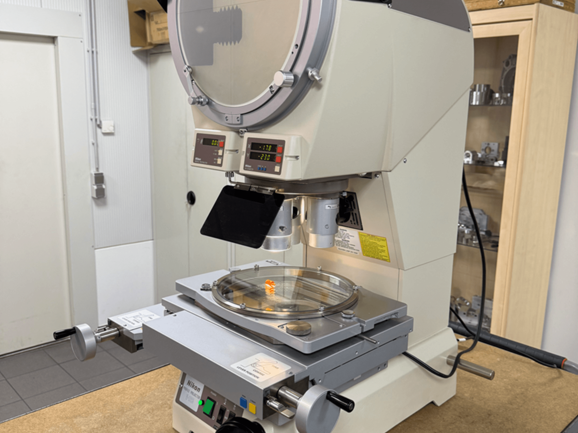 Nikoni mudeli mikroskoop esiplaanilt, millel on digitaalsed näidikud, reguleeritav statiiv ja ümmargune klaasplaat.