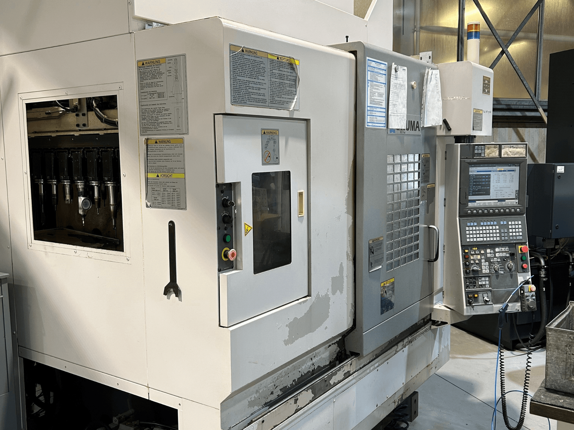 UMA CNC-pingi esivaade koos nähtavate tööriistahoidjate, juhtpaneeli, hoiatussiltide ja kasutamisnuppudega.