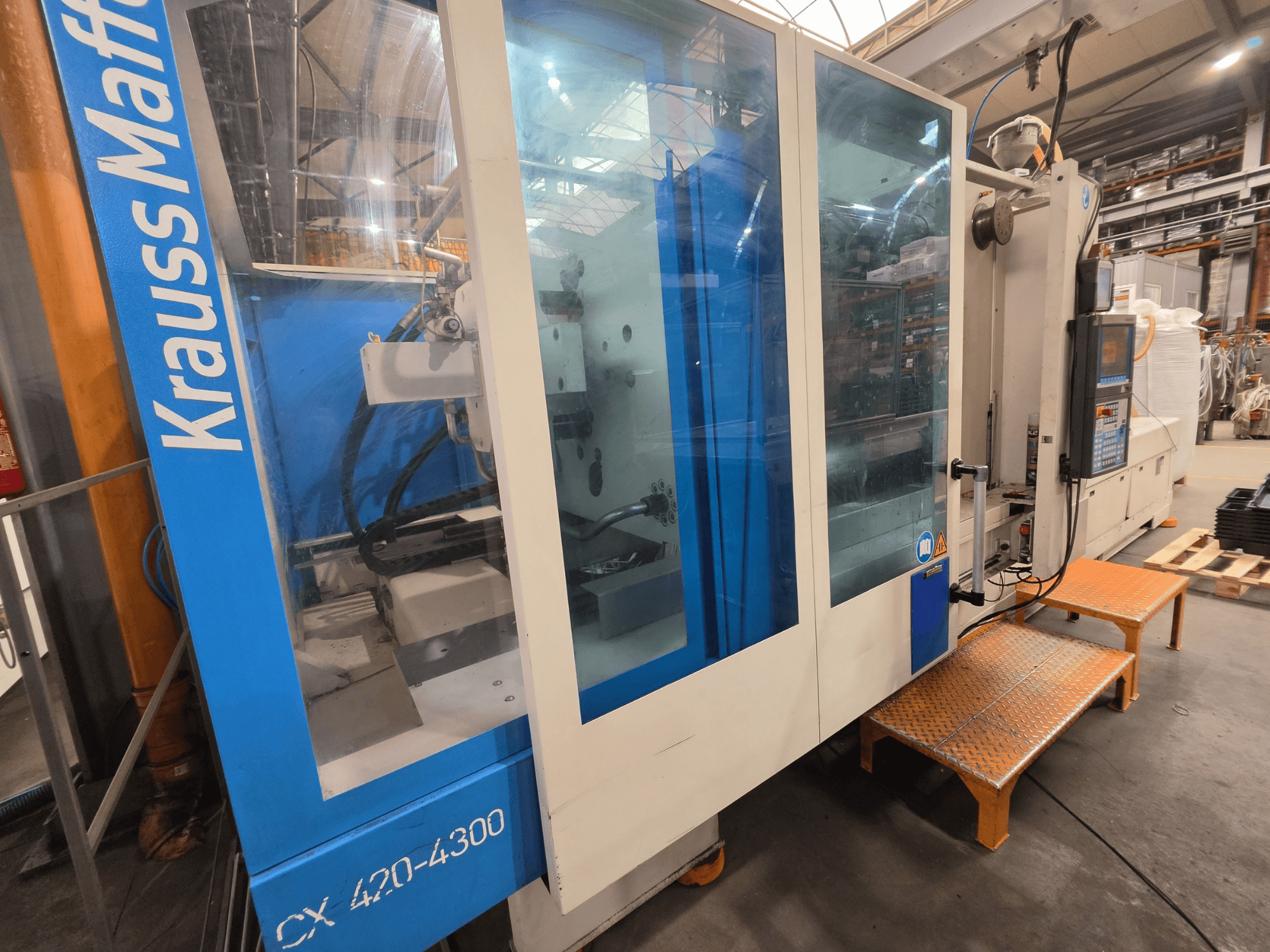 Krauss Maffei CX 420-4300 hüdrauliline survevalu masin, külgvaade, kus on näidatud juhtpaneel ja läbipaistvad paneelid.