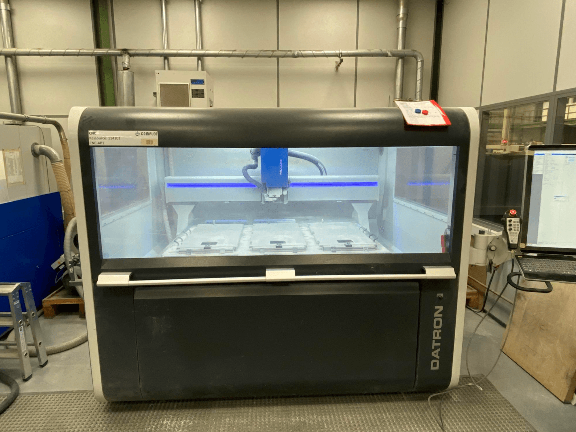 Datron MLCube B vertikaalne töötlemiskeskus, esiplaanil, kus on näha masina sisemus ja juhtpaneel.