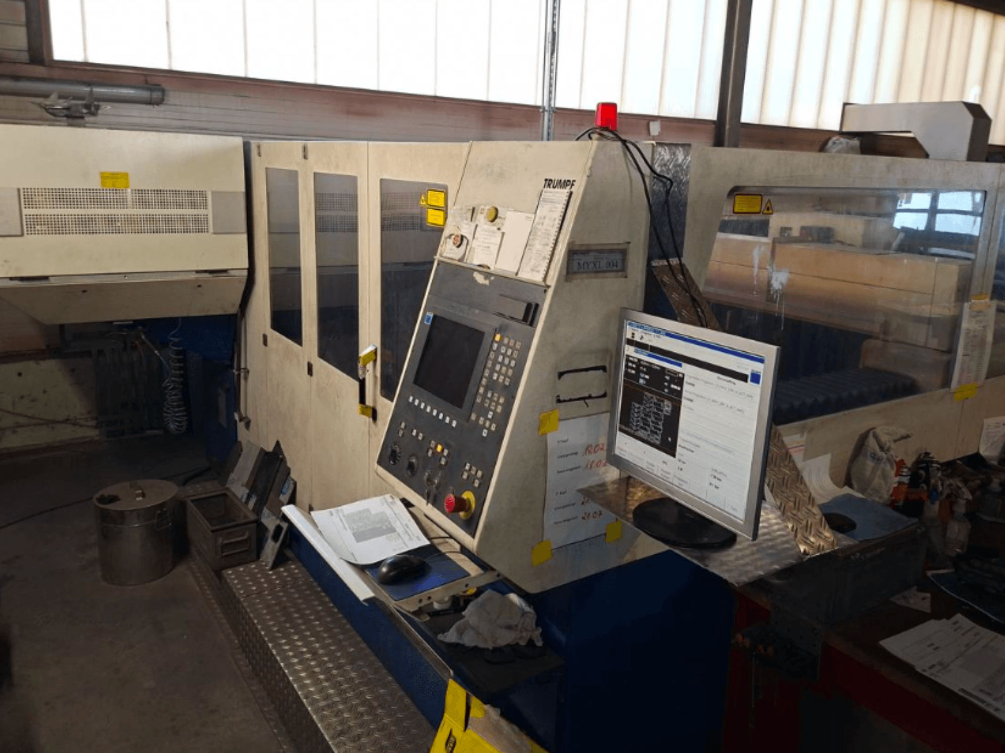 TRUMPF Trumatic L 4030 CO2-laserlõikepink, esiplaanil on juhtpaneel ja monitor, tööruumi detailid on nähtavad.