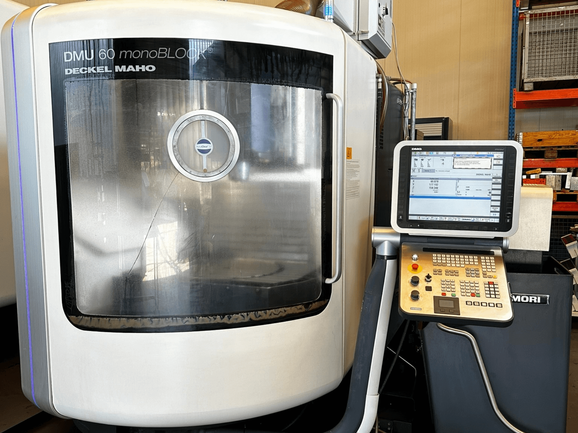 DMG MORI DMU 60 monoBLOCK vertikaalne töötlemiskeskus, esiplaanil, kus on näidatud puutetundlik juhtpaneel ja peegeldav aken.