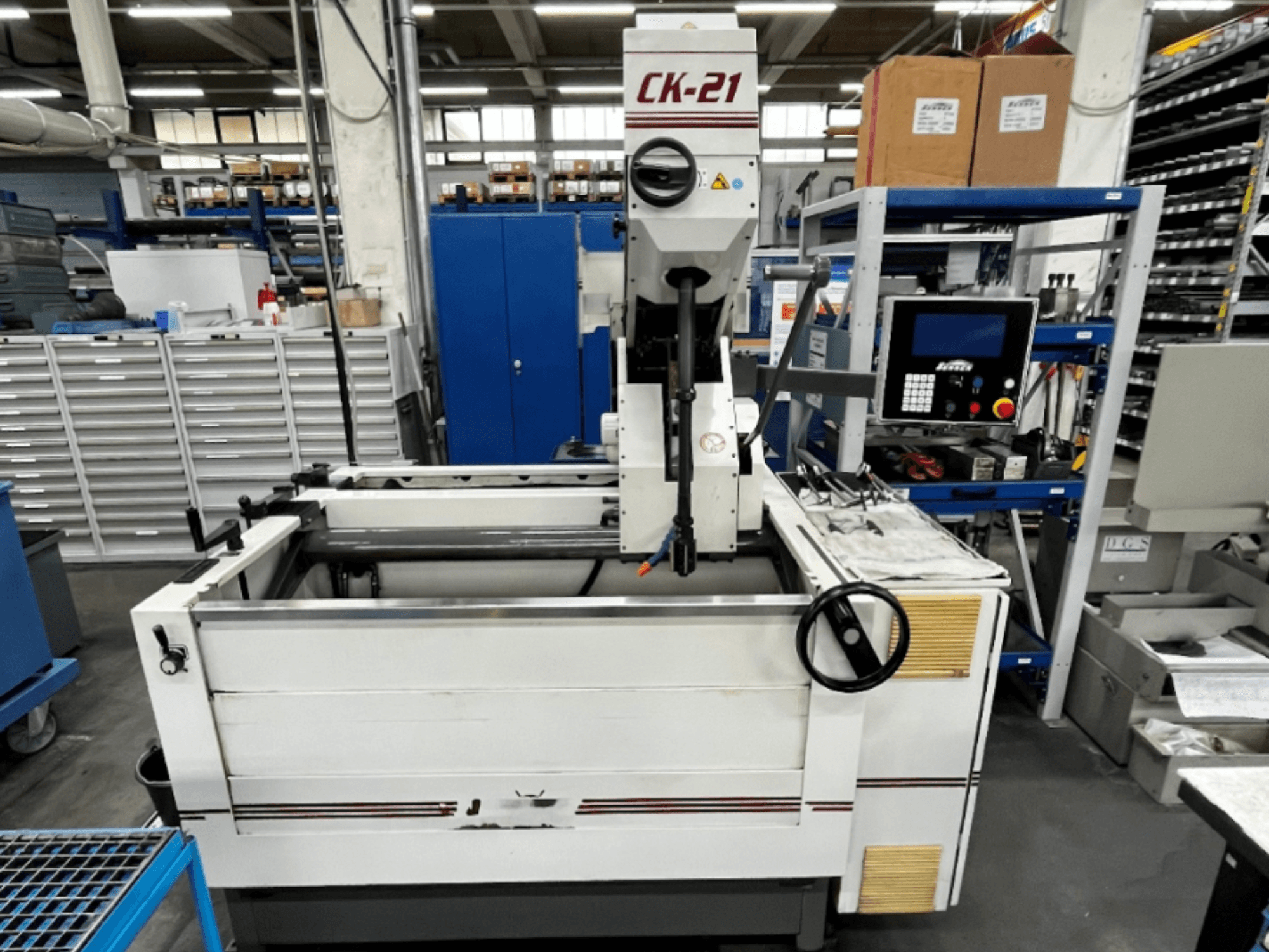 Sunnen CK-21-CC vertikaalne lihvimismasin esiplaanil, taustal juhtimispuldid, lihvimisala ja abiseadmed.