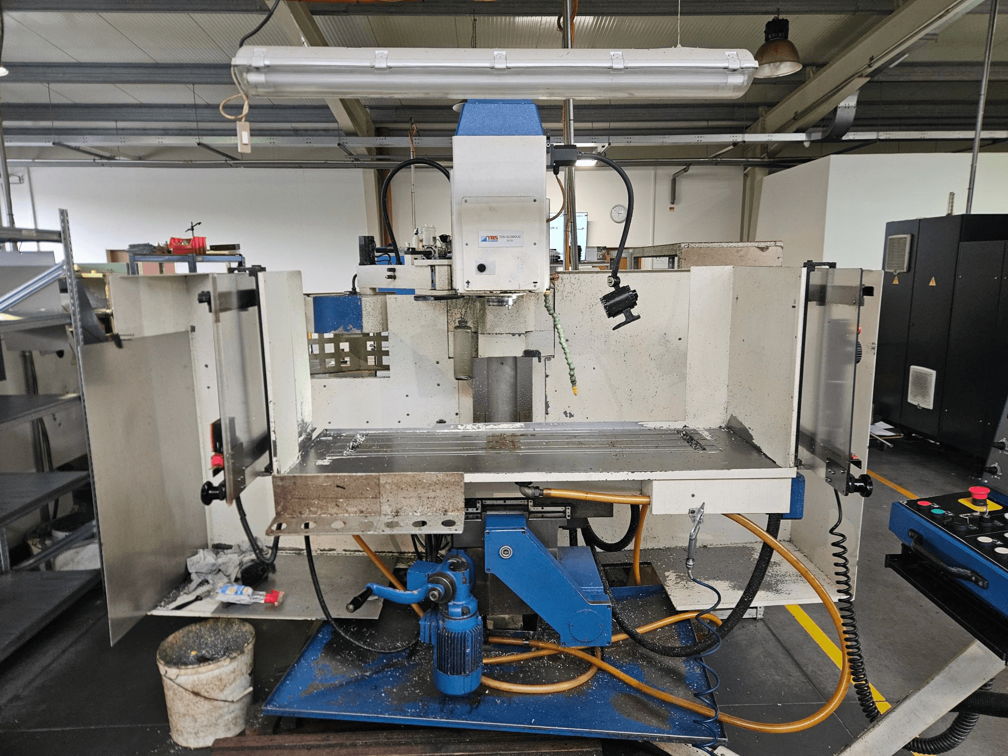 TOS Olomouc FV30 CNC Vertikaalne töötluskeskus töökojas, esiplaanil on näidatud juhtpaneel, töölaud ja jahutussüsteem.