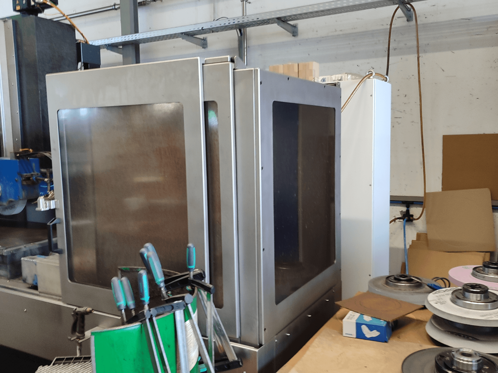 HEINZ STÖCKEL FD 1560 NC-T pindade lihvimismasin, külgvaade, kus on näidatud metallkorpus ja lihvimiskomponendid töökojas.