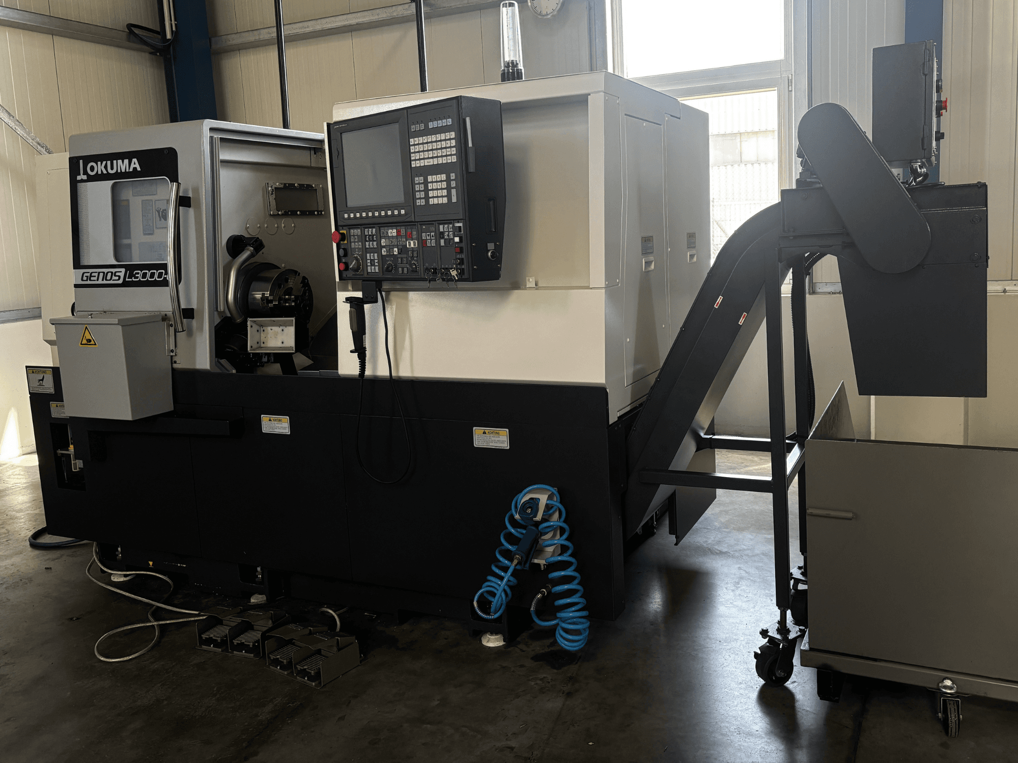 Okuma GENOS L3000-e horisontaalne treipink, vaade eest, millel on näha juhtpaneel, konveier ja spindli piirkond.