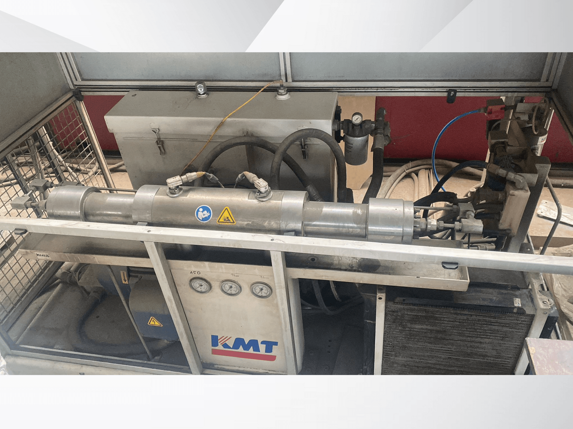 KMT hüdraulikamasin esiplaanil, millel on manomeetrid, voolikud ja metallist korpus, mis on ideaalne tööstuslikeks rakendusteks.