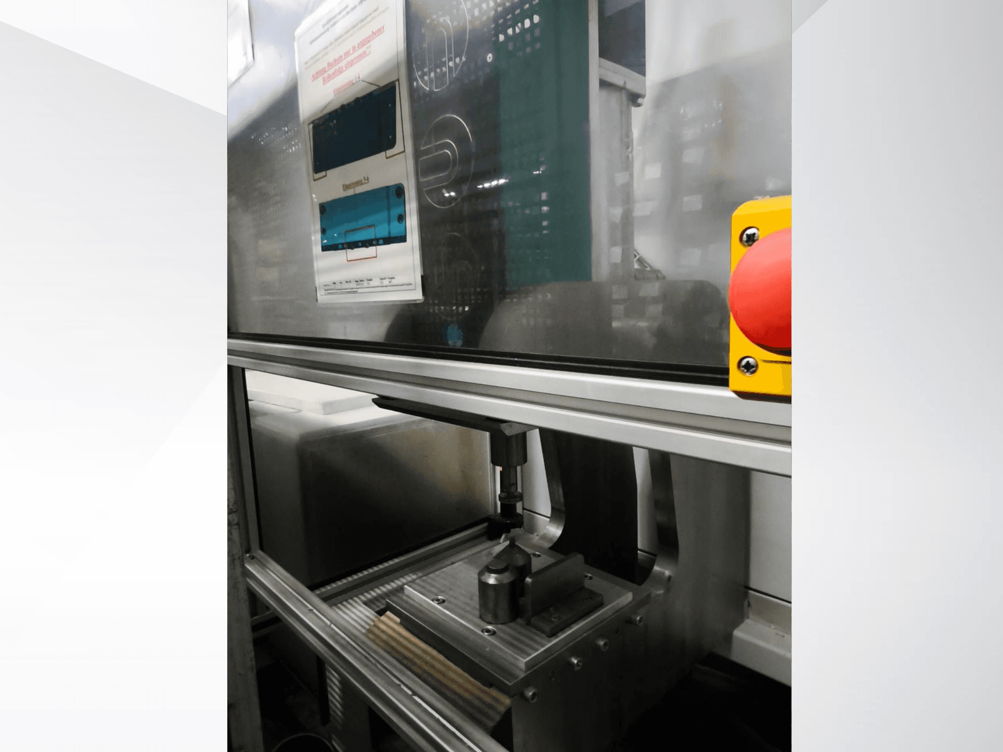 EMS Automation Buchsenpresse tööpinkide esiplaanil, kus on näha pressimismehhanism ja ohutusnupp.