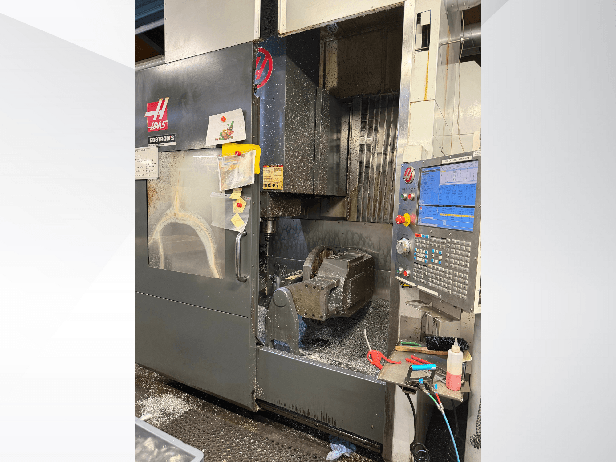 Haasi CNC-tööpink mudel EDSTROM S, esiplaanil, kus on näha metalltöödeldis, juhtpaneel ja metallilaastud sees.