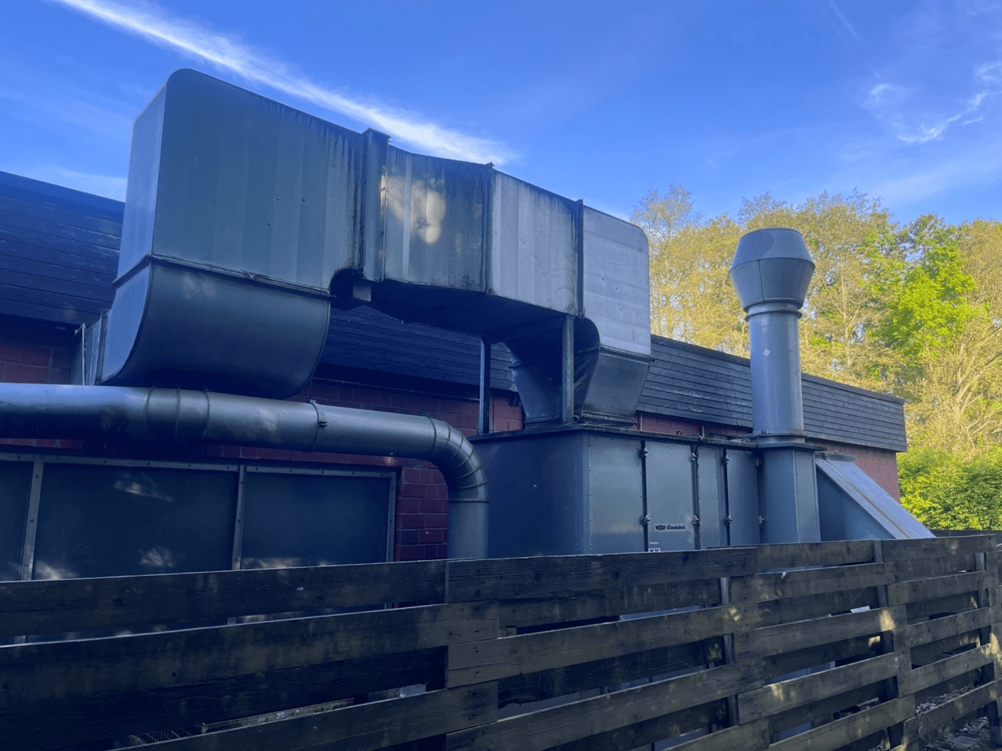 Tööstuslik ventilatsioonisüsteem metallist kanalitega, külgvaade; sisaldab nelinurkset ja silindrilist korstnat, roheline viimistlus.