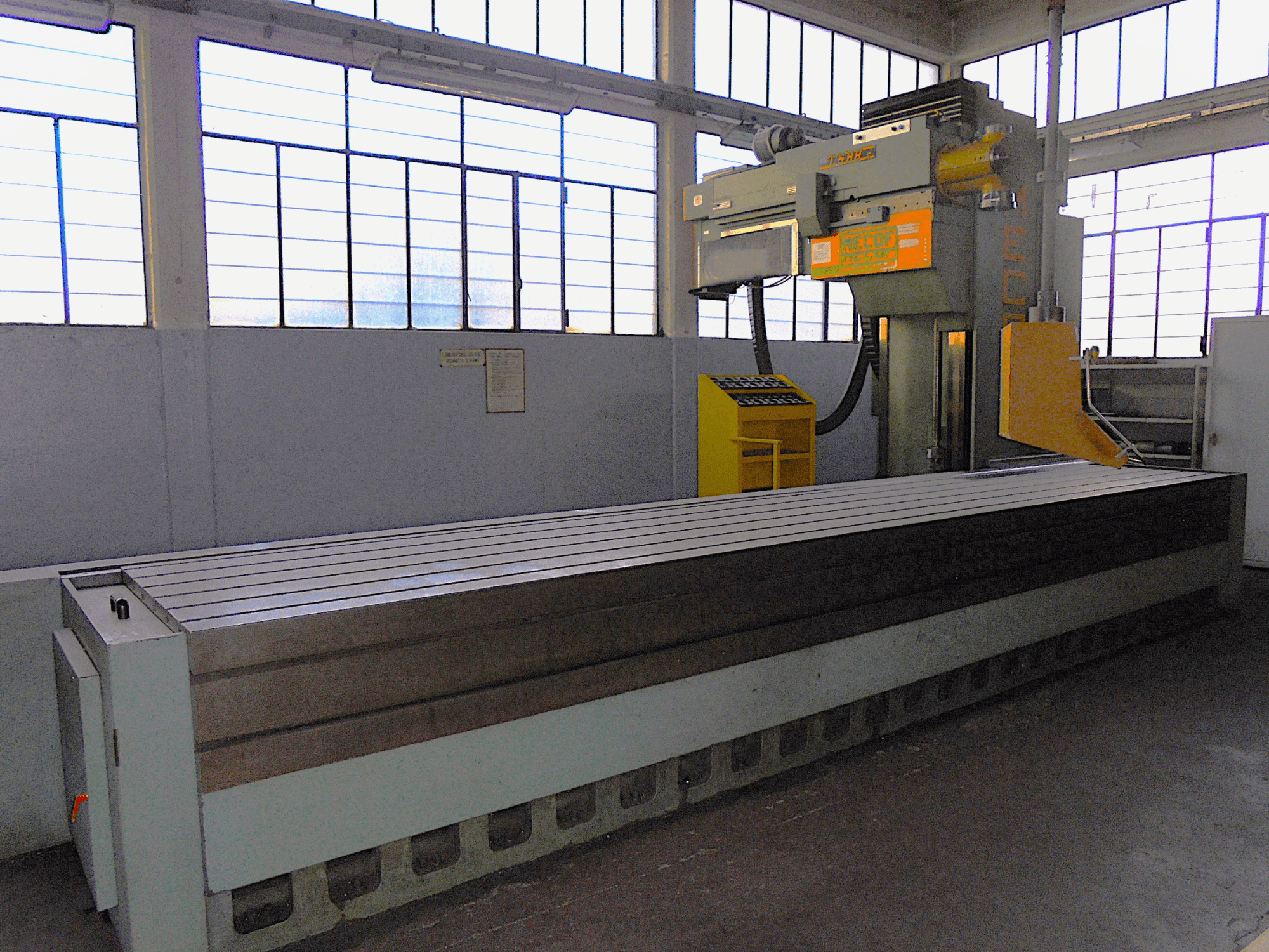 Tundmatu kaubamärk, vertikaalne freespink tehases, külgvaade, millel on suur laud soonelise pinna ja juhtpaneeliga.