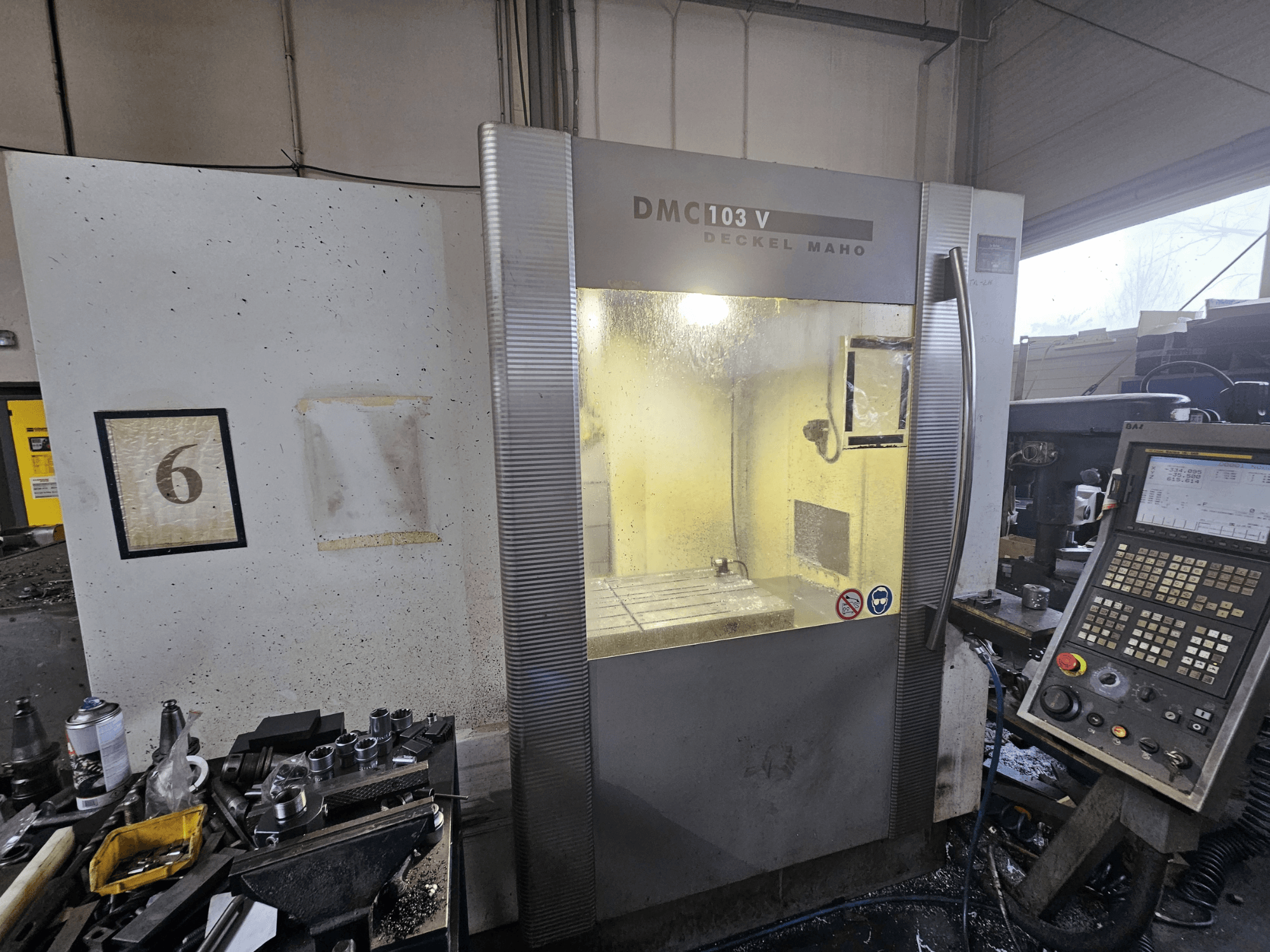 Deckel Maho DMC 103 V CNC-pingi esiplaan, millel on näidatud juhtpaneel, tööala ja nummerdatud indikaator "6".