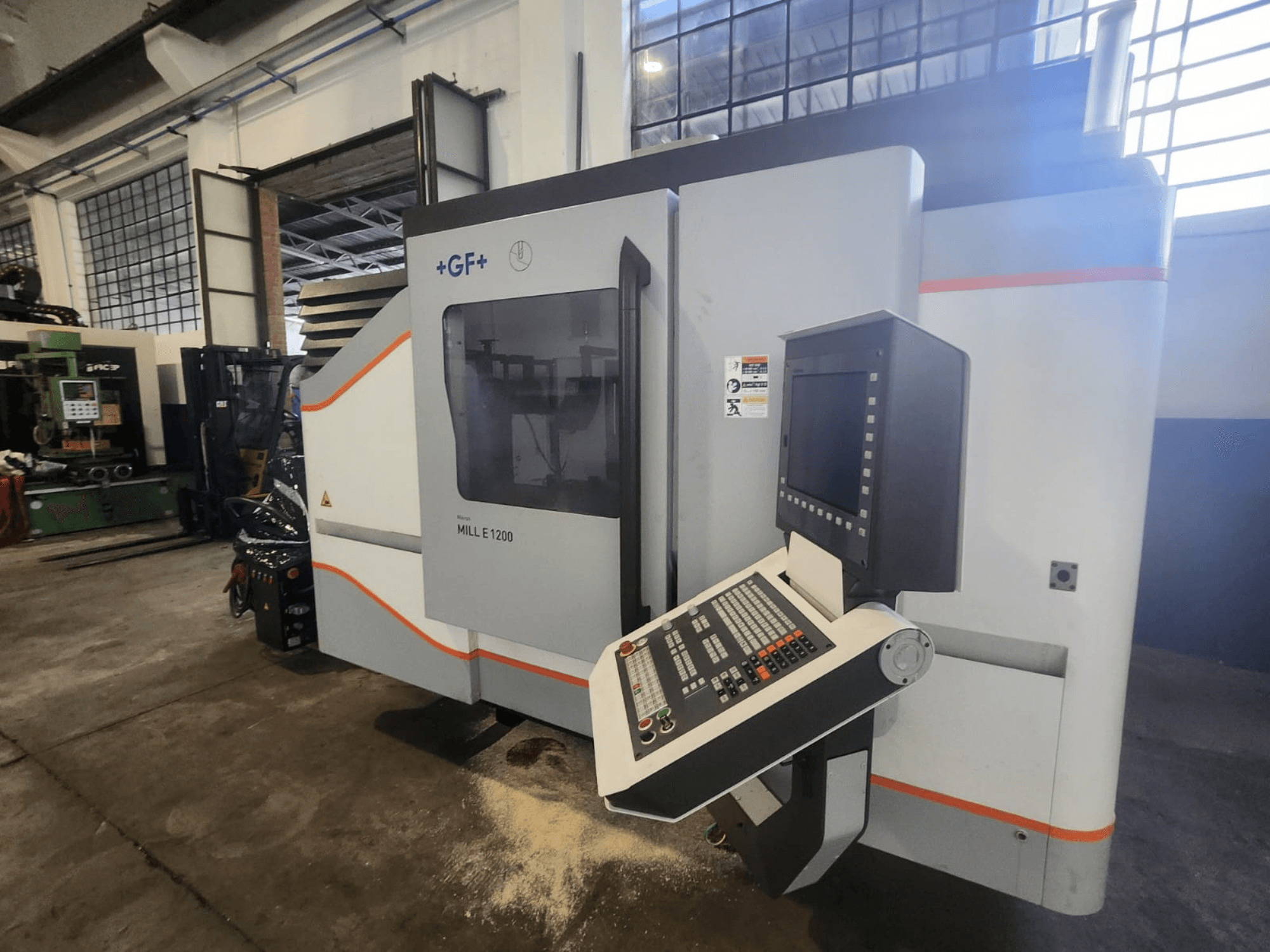 GF MILL E1200, freespingi esivaade koos juhtpaneeli, ekraani ja ohutussiltidega, töökoja seadistuses.