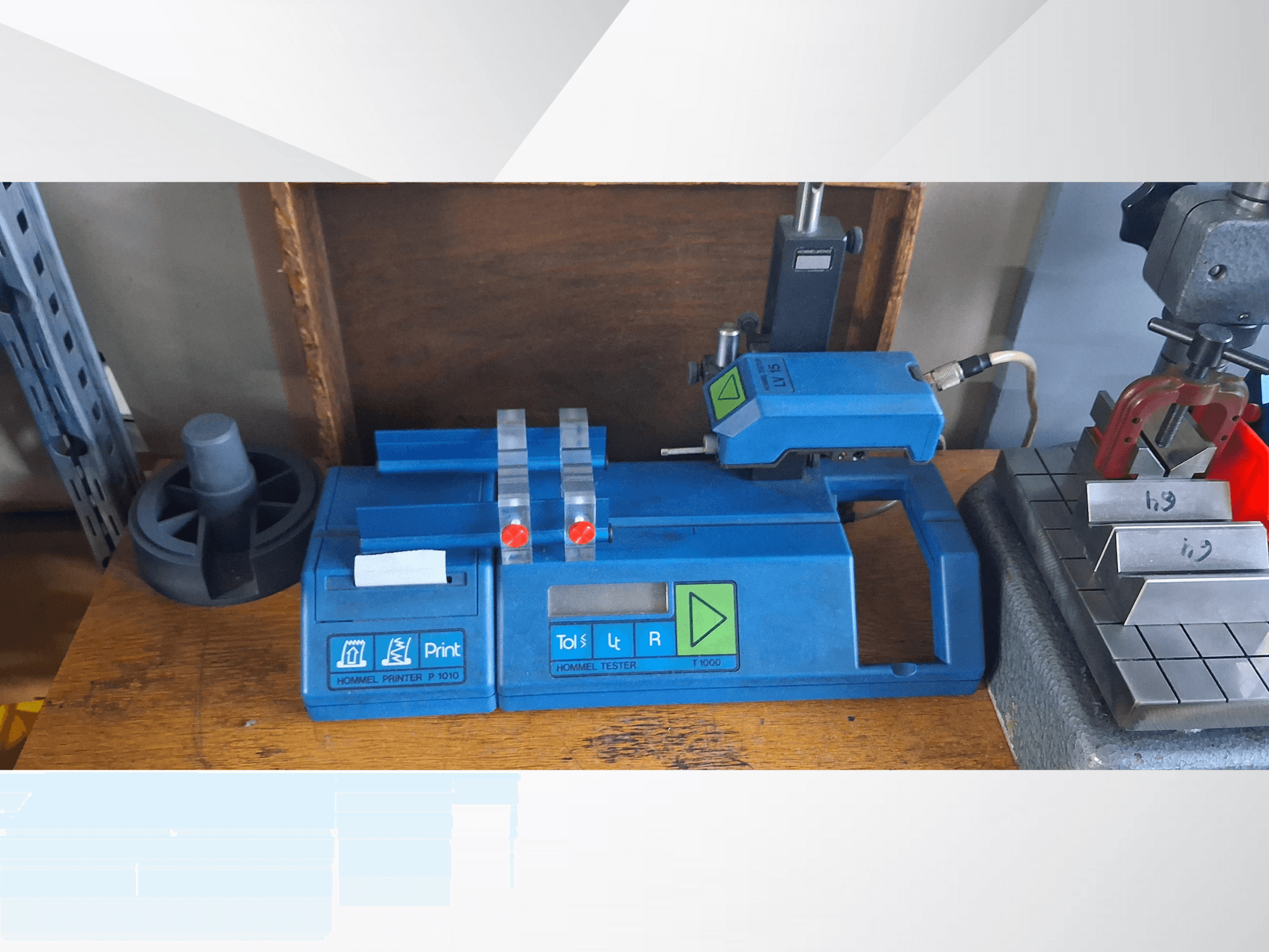 Sinine Hommel T 1000 printer ja T 1 010 tester punaste nuppudega, vaadatuna eestpoolt metallplokkidega töölaual.