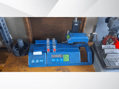 Sinine Hommel T 1000 printer ja T 1 010 tester punaste nuppudega, vaadatuna eestpoolt metallplokkidega töölaual.