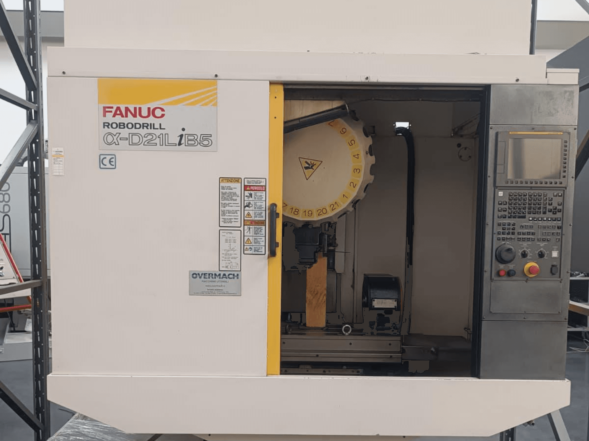 FANUC Robodrill α-D21LiB5, esivaade; CNC-tööpink, mille tööriistahoidja, juhtpaneel ja ohutushoiatused on nähtavad.