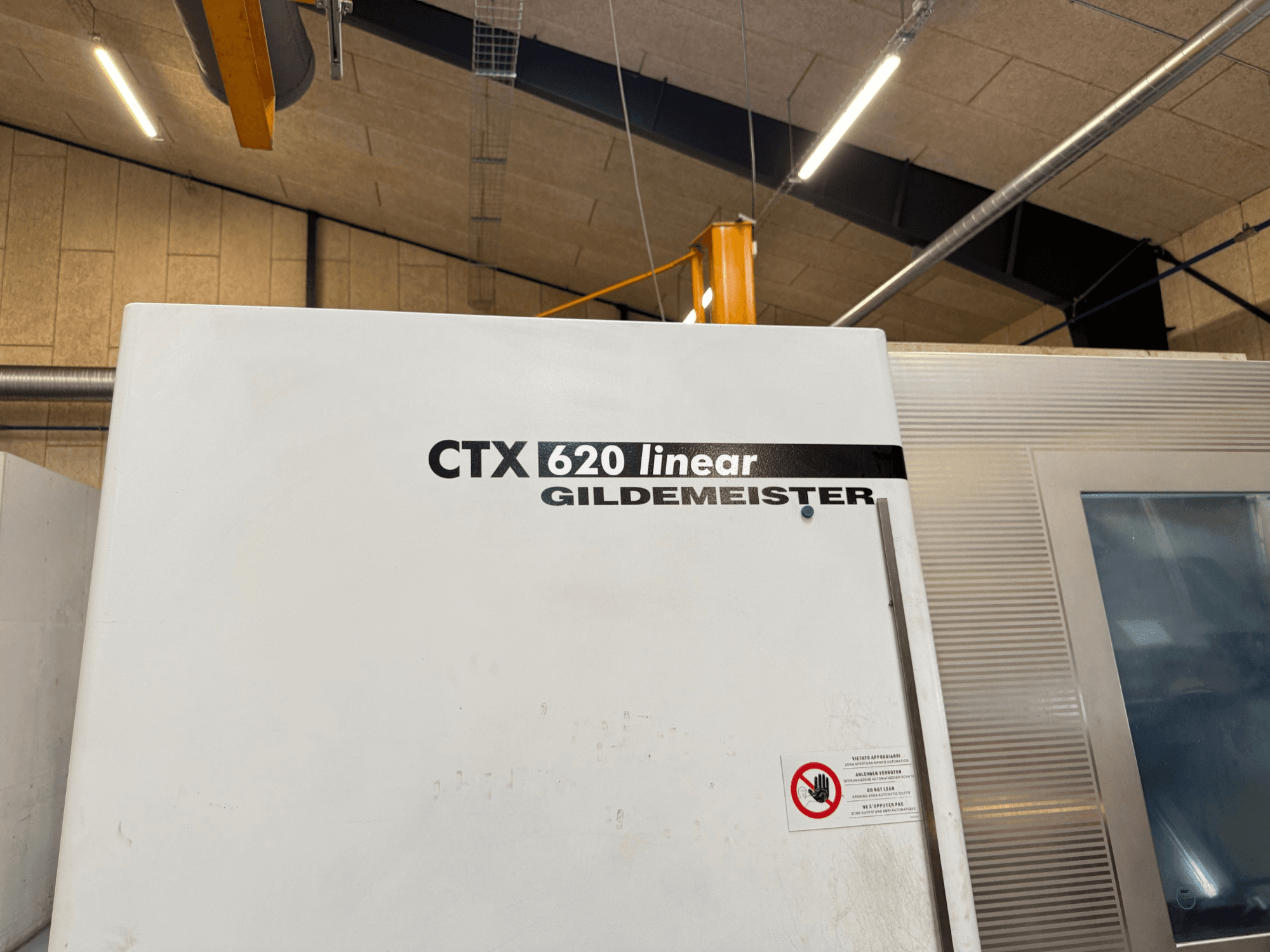 CTX 620 Linear Gildemeister masina külgvaade, millel on valge välispind ja ohutushoiatussildid.