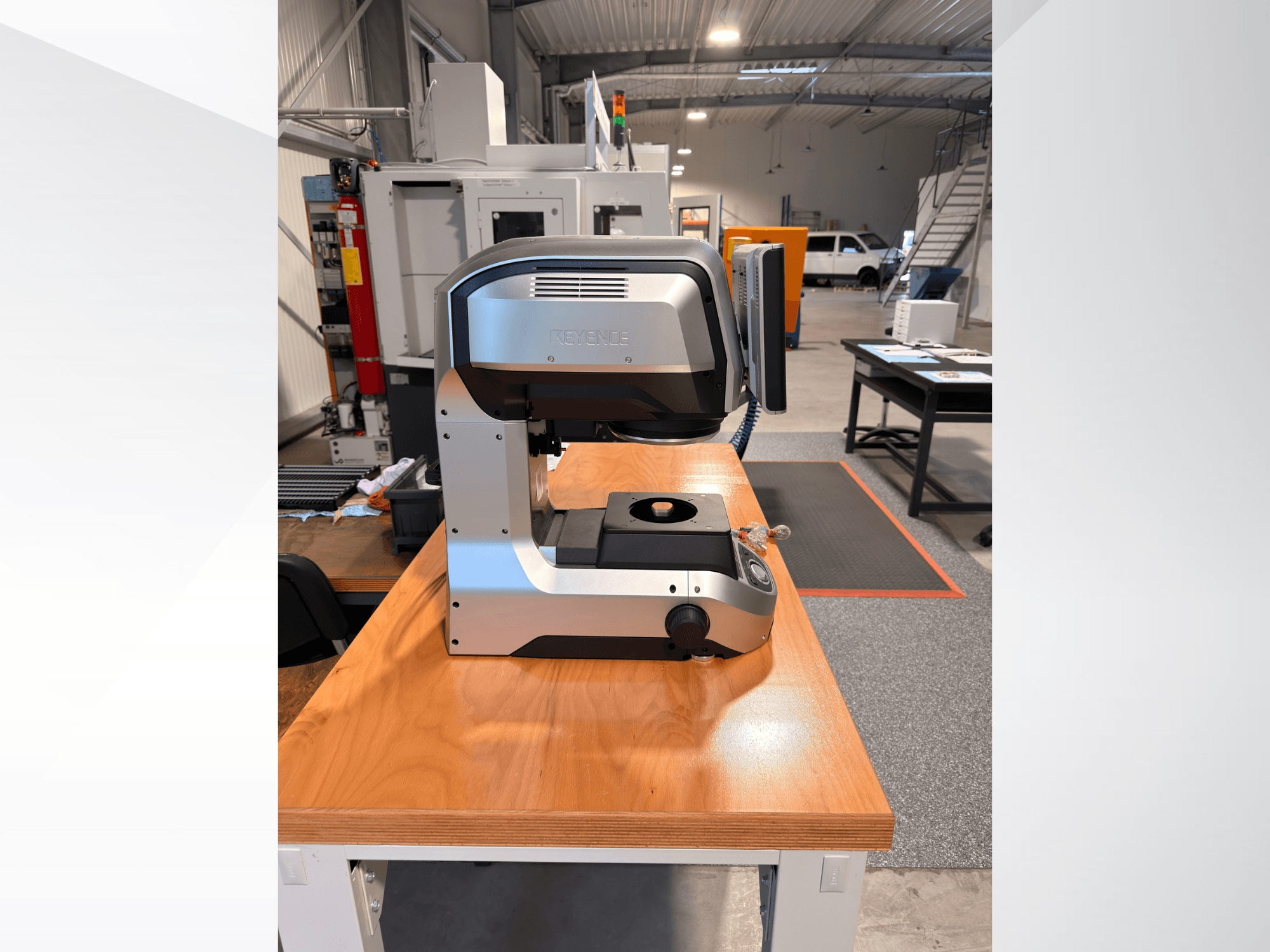 KEYENCE IM-8005 optilise mõõteseadme vaade eestpoolt puidust laual, millel on näha seadme elegantne disain ja kasutajaliides.
