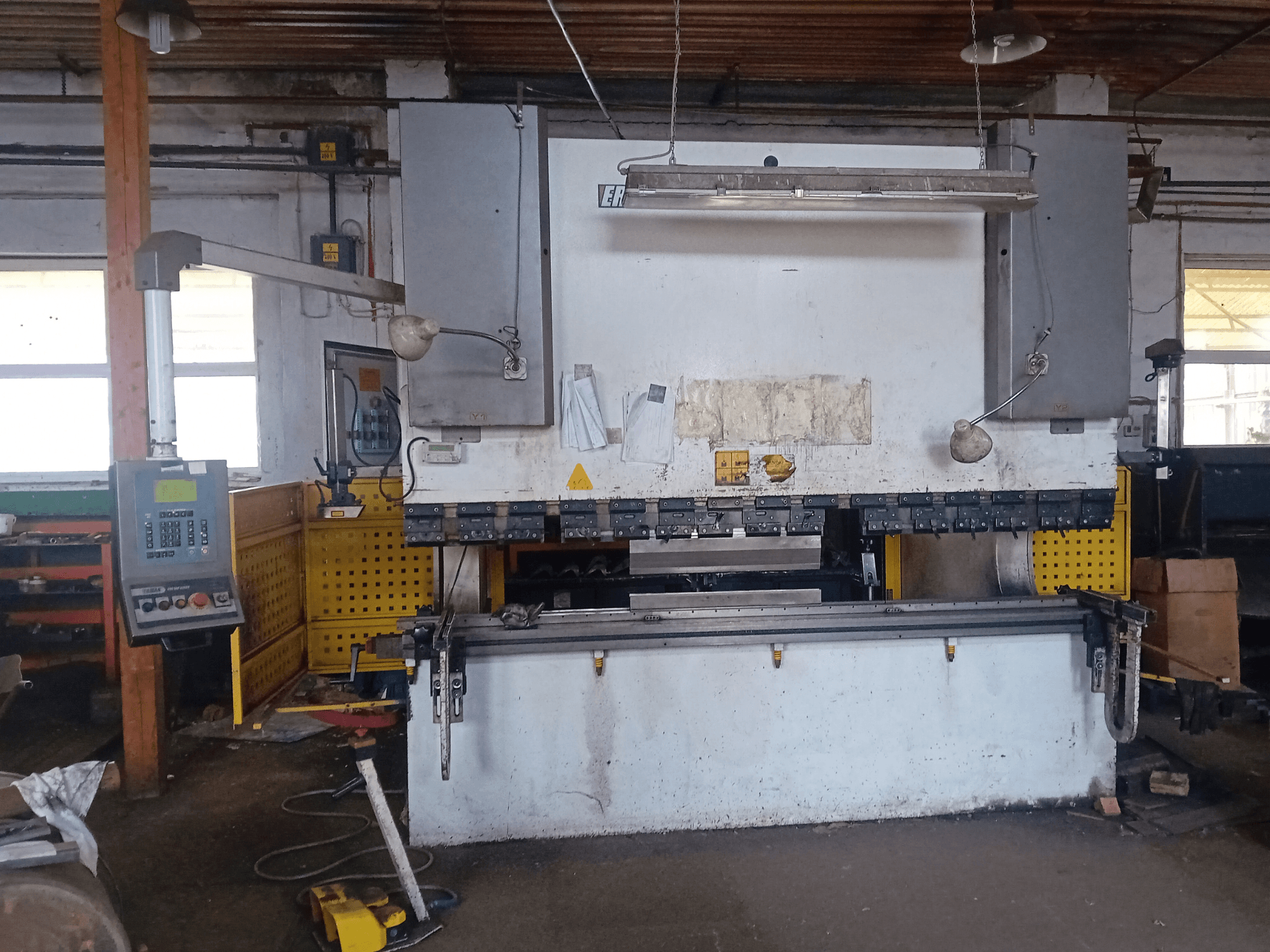 ERMAK CNC HAP 3100x300 hüdrauliline press esiplaanil, millel on juhtpaneel ja tööpink töökojas.