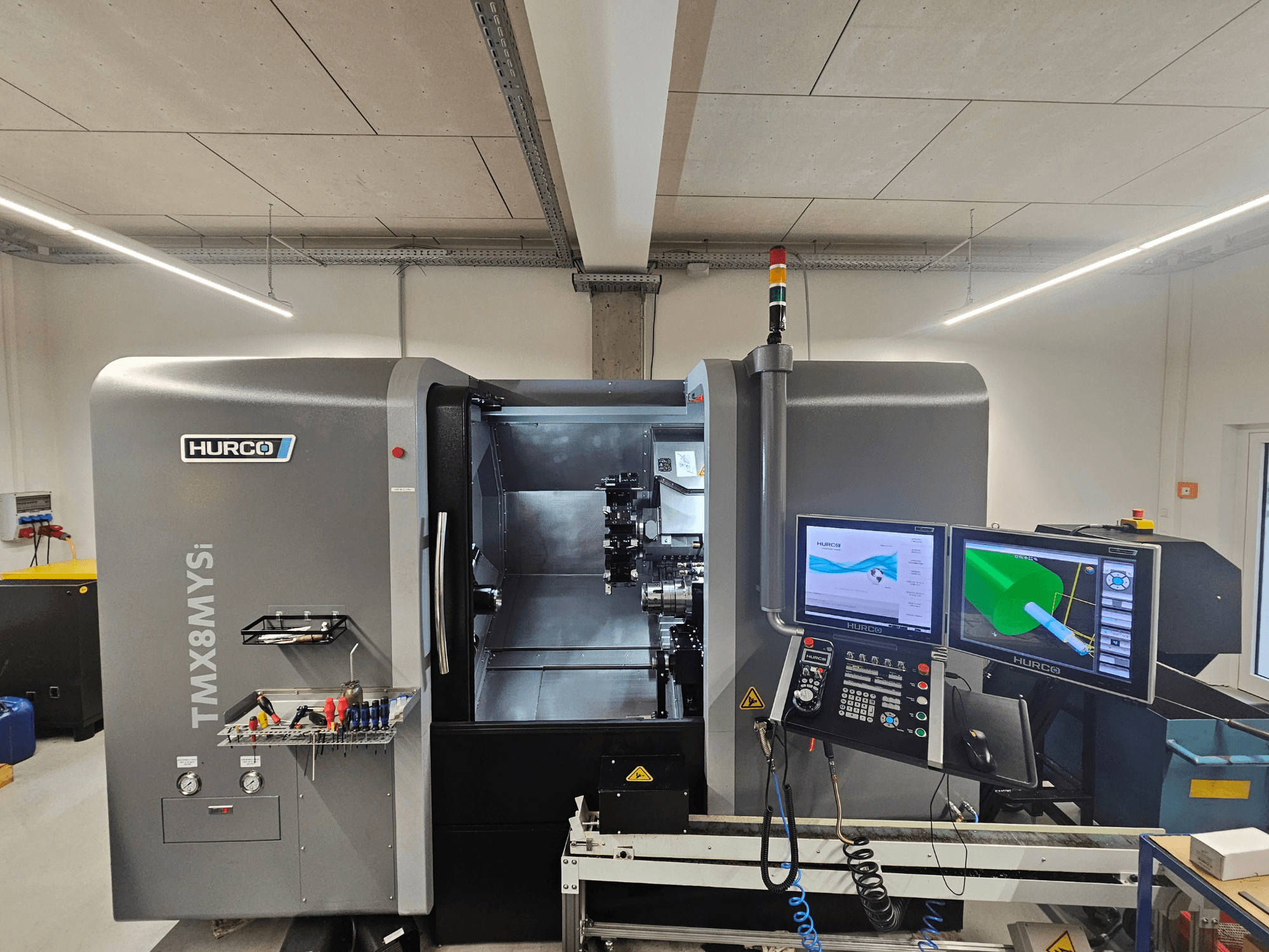 Hurco TMX 8 MYSi treipingi keskus töökojas, millel on kaks monitori, juhtpaneel ja tööriistad küljel.