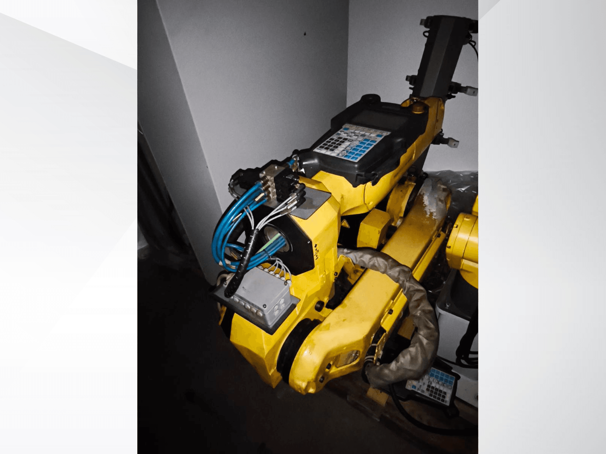 FANUC M-20iA robotkäsi külgvaates, kus on näha kollane kere, juhtpaneel ja ühendatud juhtmestik.