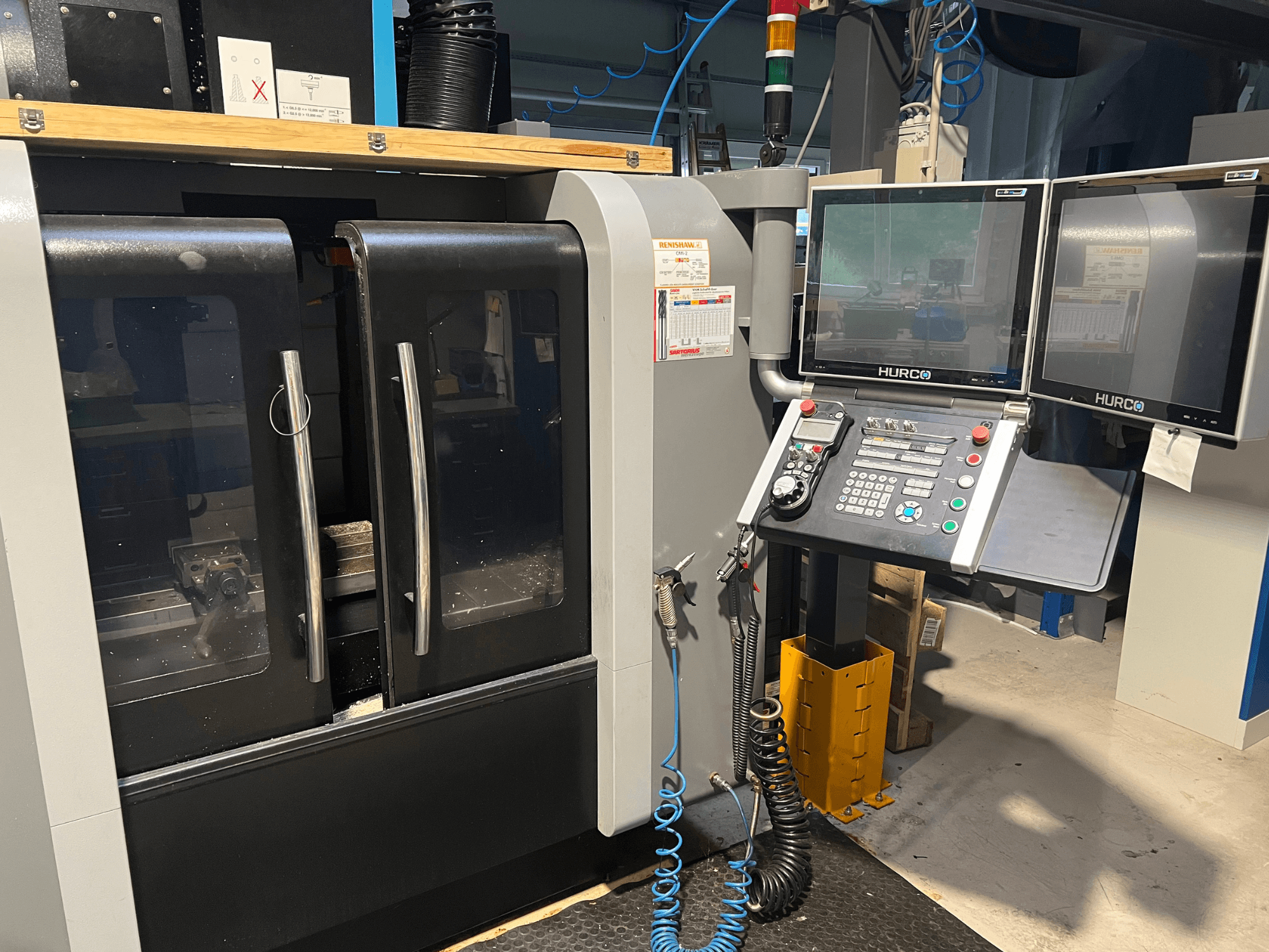 Hurco CNC-pingi esivaade kahe monitori ja juhtpaneeliga. Omab läbipaistvaid uksi ja nähtavat töötlemisala seestpoolt.