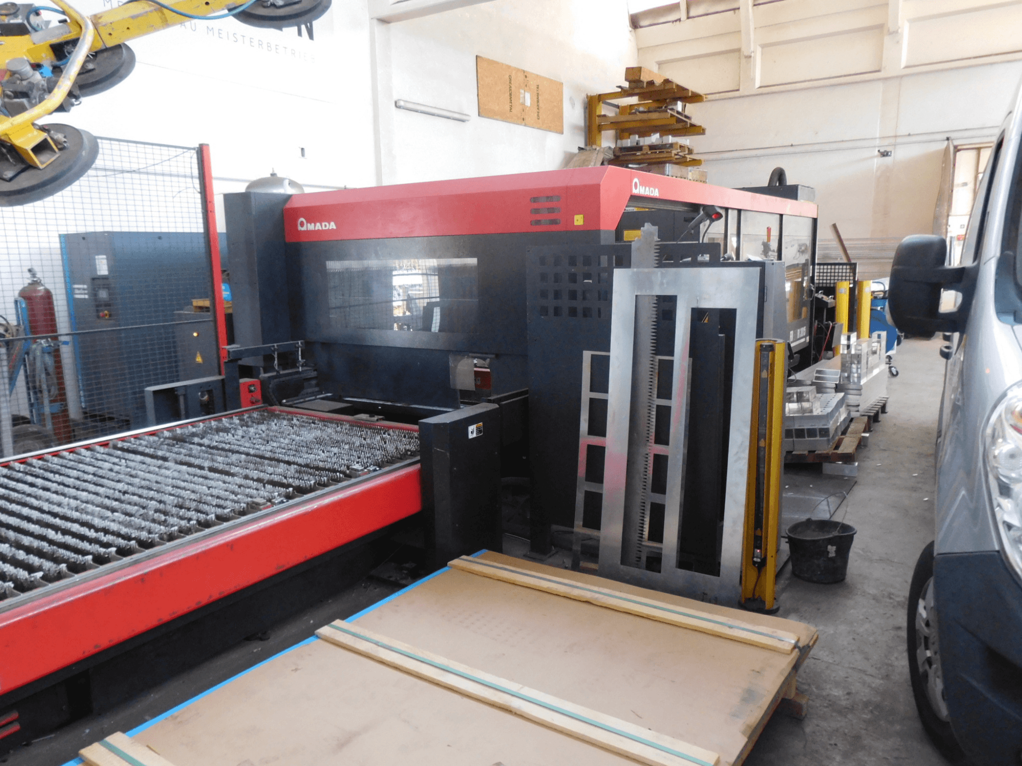 AMADA FO-3015 II RI CO2-laserlõikepingi esivaade, millel on lõikeplaat ja seda ümbritsev tööala.