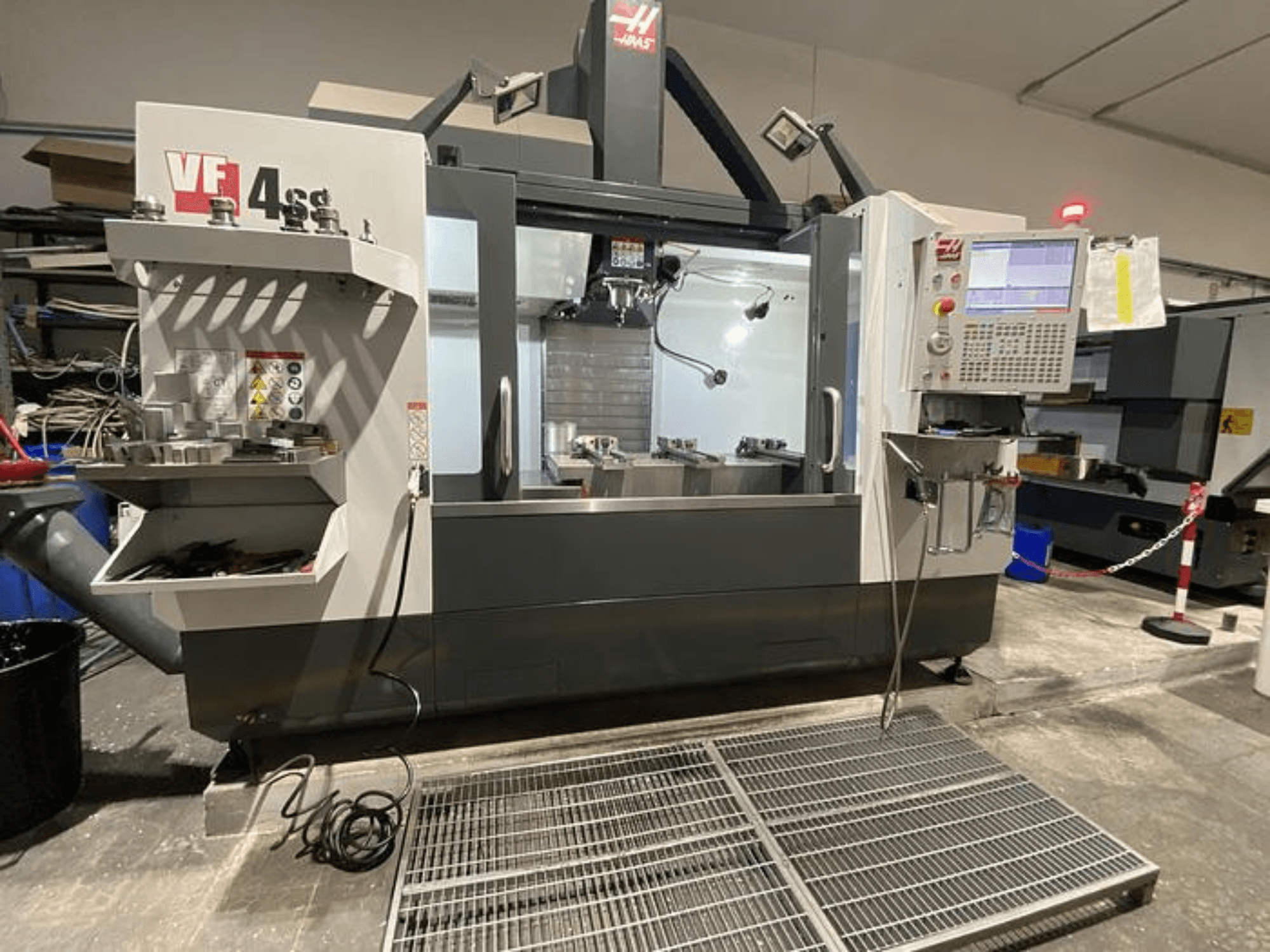 Haas VF-4SS CNC-freesping, esivaade, koos tööriistade hoiustamise, juhtpaneeli ja nähtava tööpiirkonnaga töökojas.