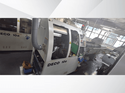 DECO 10e CNC masin külgvaates, millel on juhtpaneel, roheline sisemus ja ühendatud väljalasketoru.