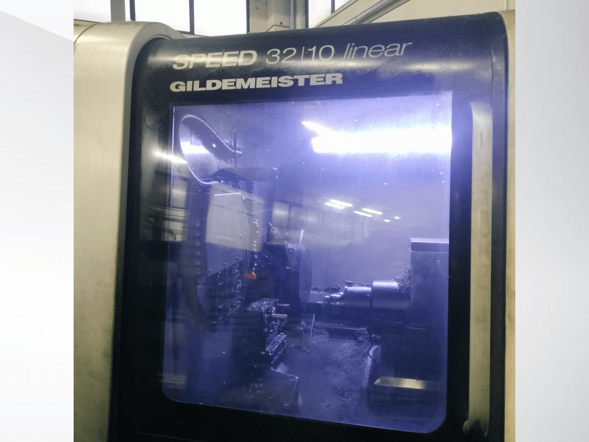 Gildemeister SPEED 3210 lineaarse CNC-pingi esivaade, kus on näha sisemised komponendid ja vedel jahutusvedelik töö ajal.