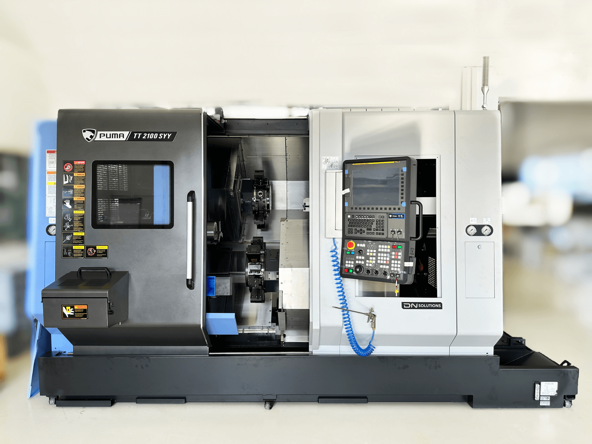 Pöörlemiskeskus DN SOLUTIONS PUMA TT2100SYY esivaade, millel on juhtpaneel ja nähtavad sisekomponendid.