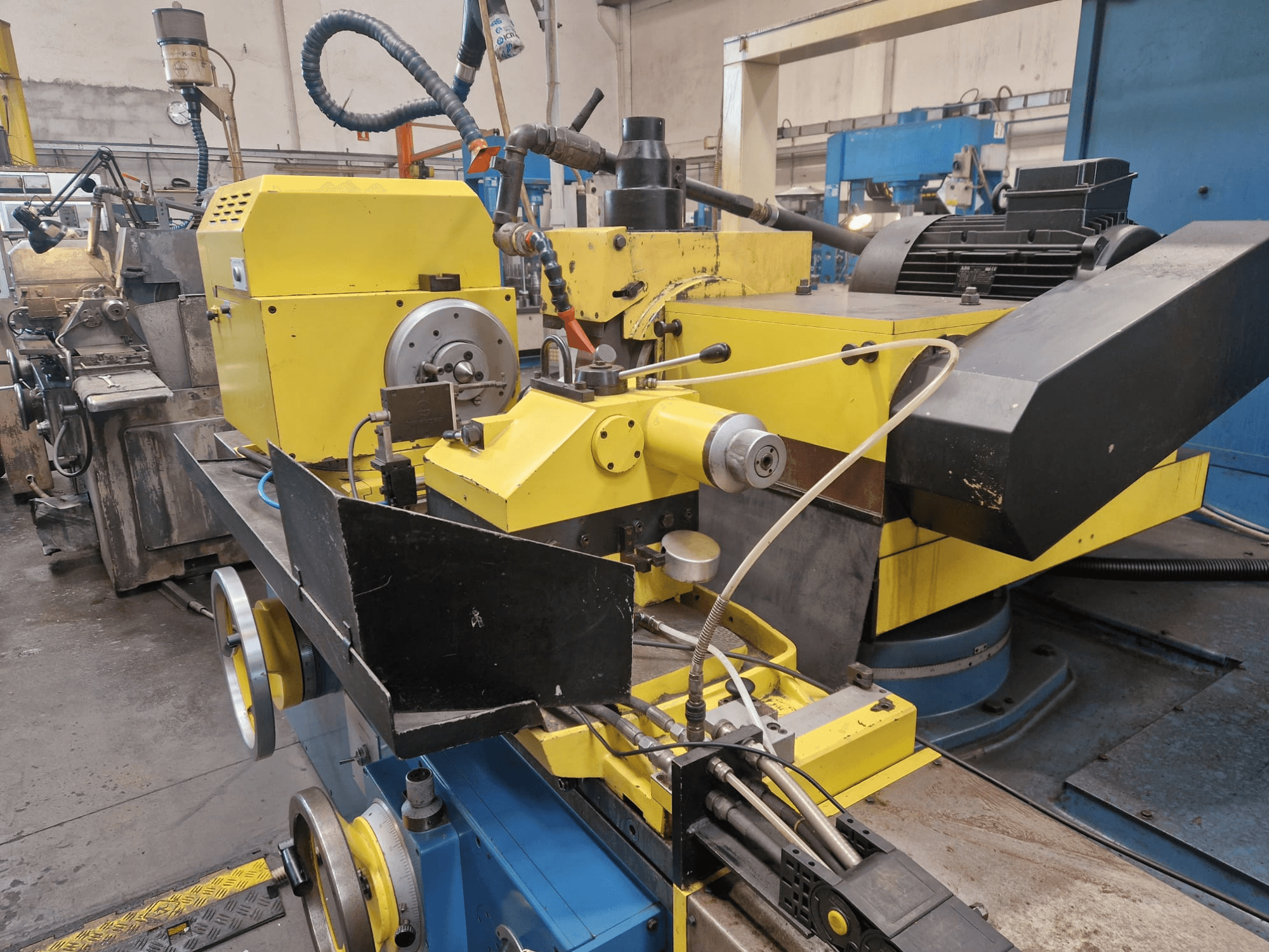 Kollane tööstuslik masin musta osaga, millel on numbrikell ja voolikud, vaadatuna eestpoolt kerge nurga all.