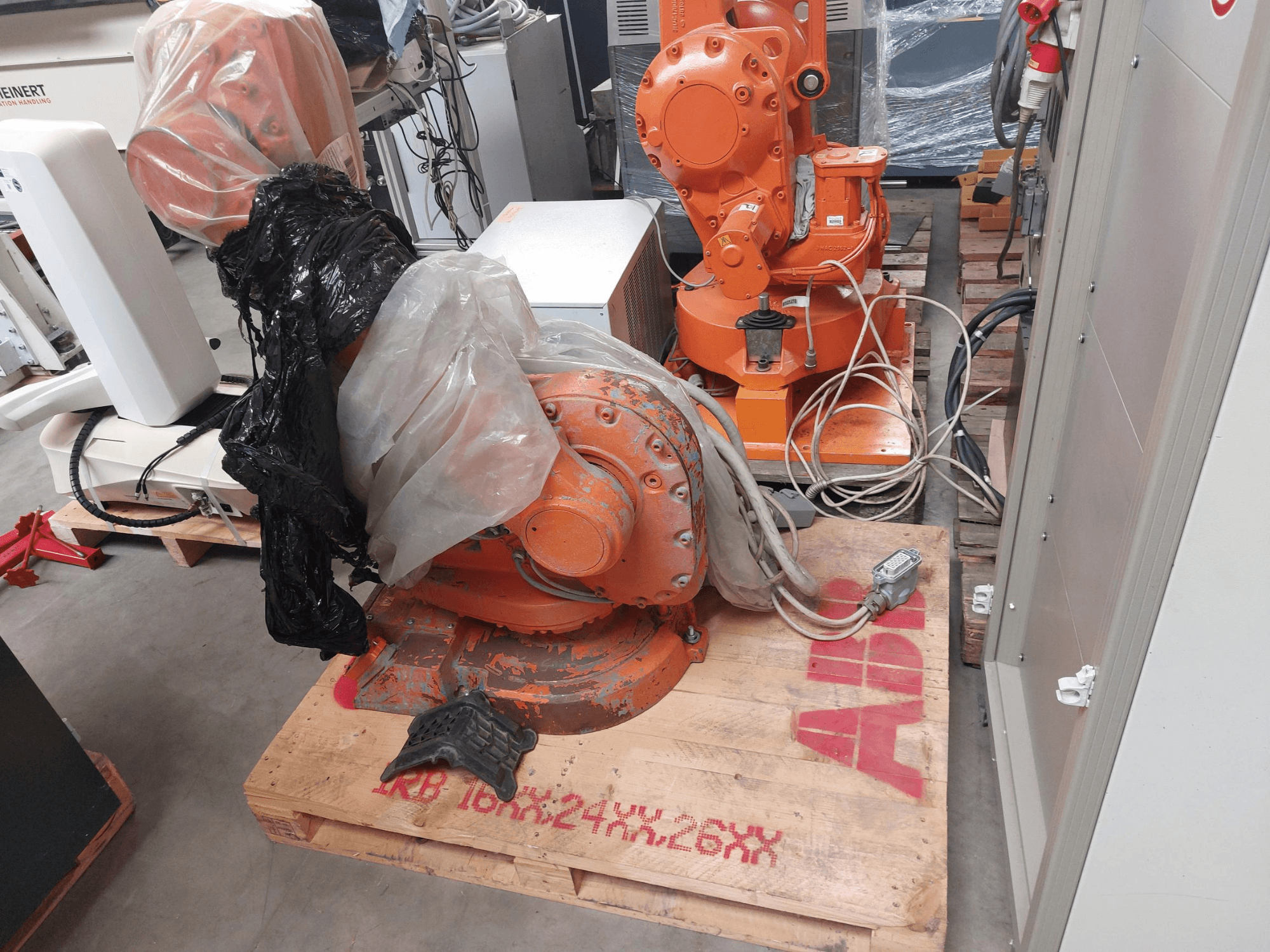 ABB IRB 1600 M2004 robotkäsi, osaliselt plastiga kaetud, eestpoolt vaadatuna, läheduses kaablid ja lisaseadmed.