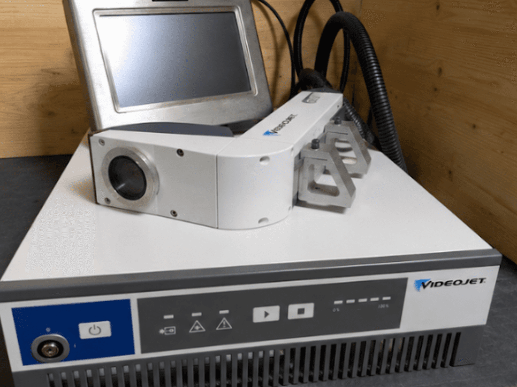Videojet 7230 lasergraveerimismasin, esivaade, kus on näidatud juhtpaneel ja laserpea koos objektiivi ja kinnitusega.