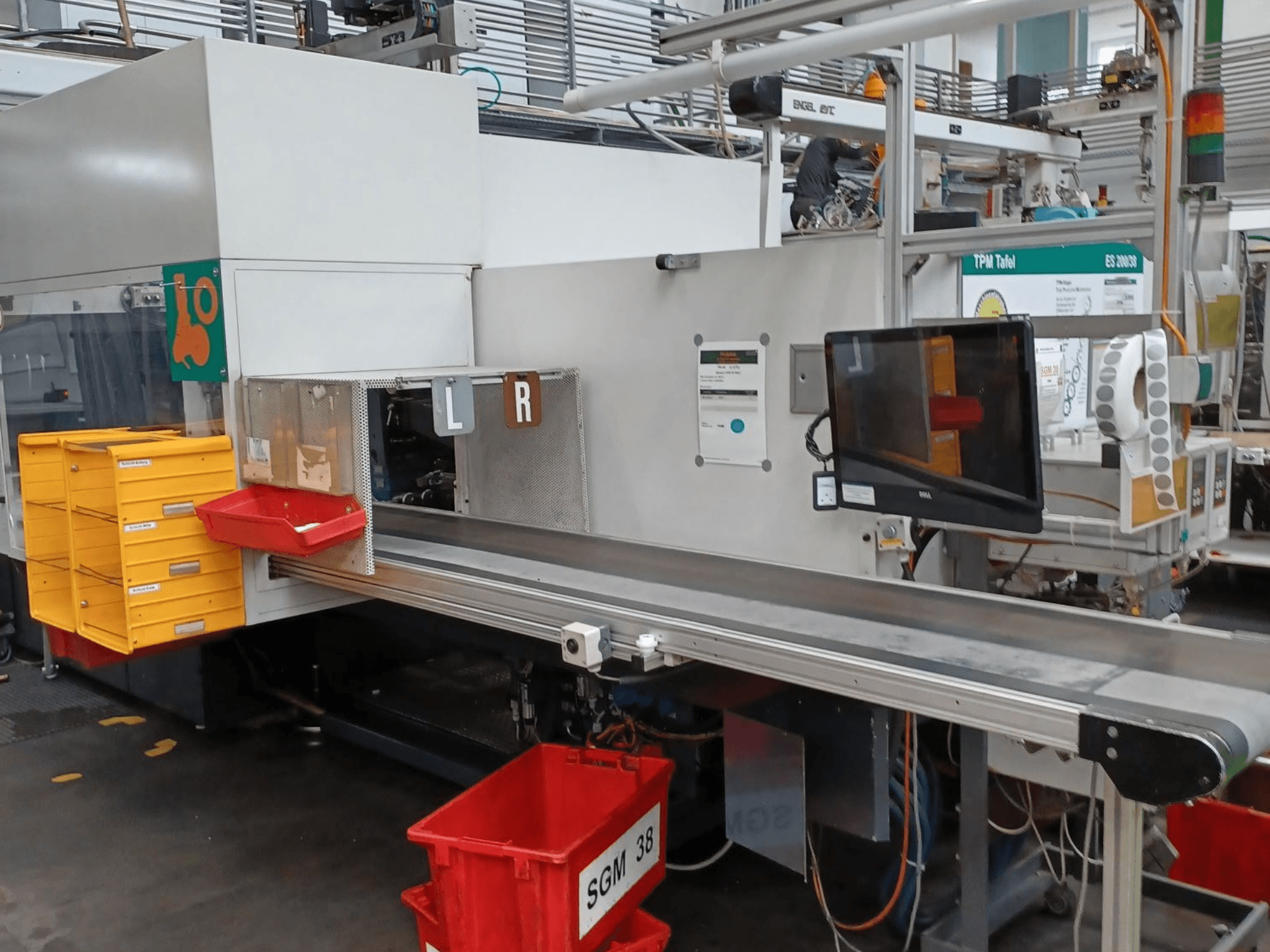Tööstuslik sorteerimismasin kollaste ja punaste kastidega, külgvaates, millel on juhtimismonitor ja sildistatud sorteerimiskohad.