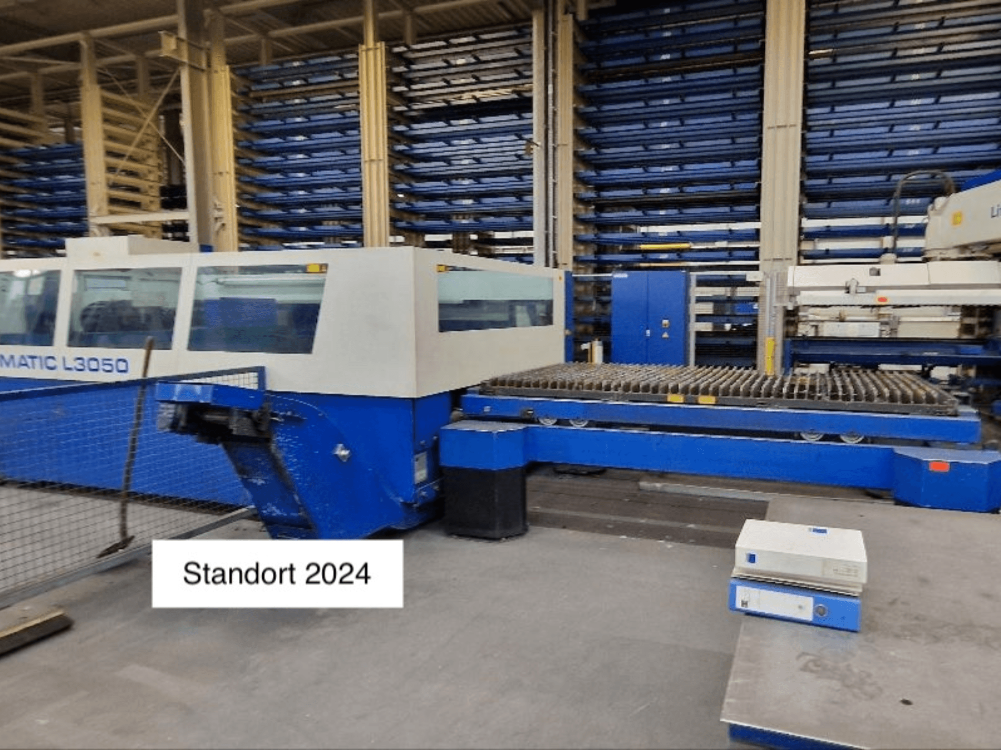 TRUMPF Trumatic L3050 CO2-laserlõikepink esiplaanil, millel on suur lõikepink ja juhtpaneel.