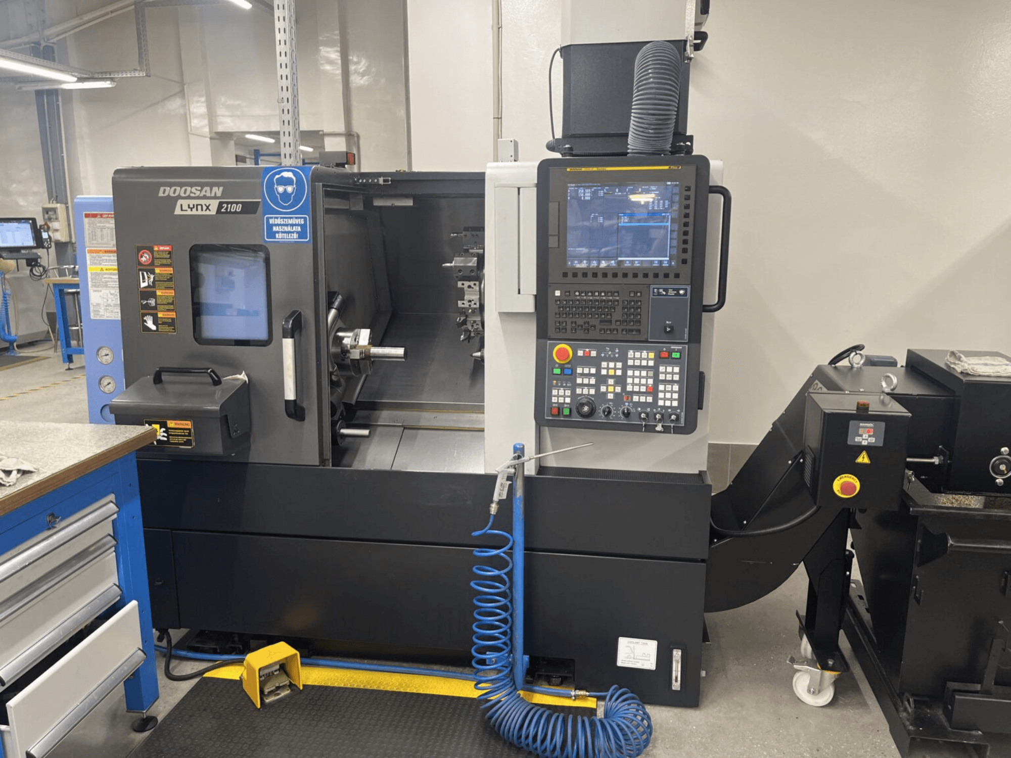 DOOSAN Lynx 2100A horisontaalse treipingi esivaade, kus on näidatud juhtpaneel ja spindli ala koos märkimisväärsete turvaelementidega.