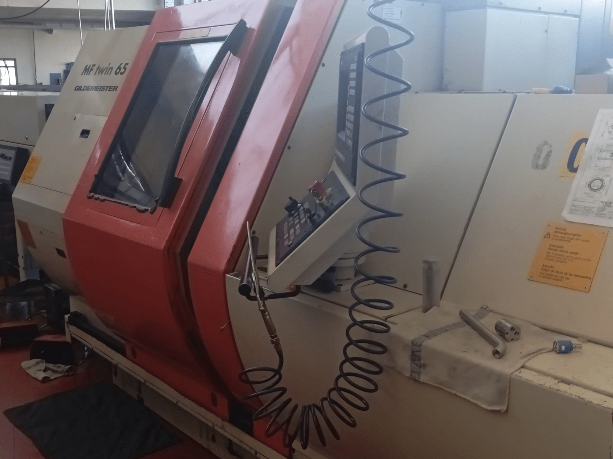 Oranžikas ja valge MF twin 65 Gliedemeister masin, esiplaanil, millel on juhtpaneel ja tööriistad lapil.