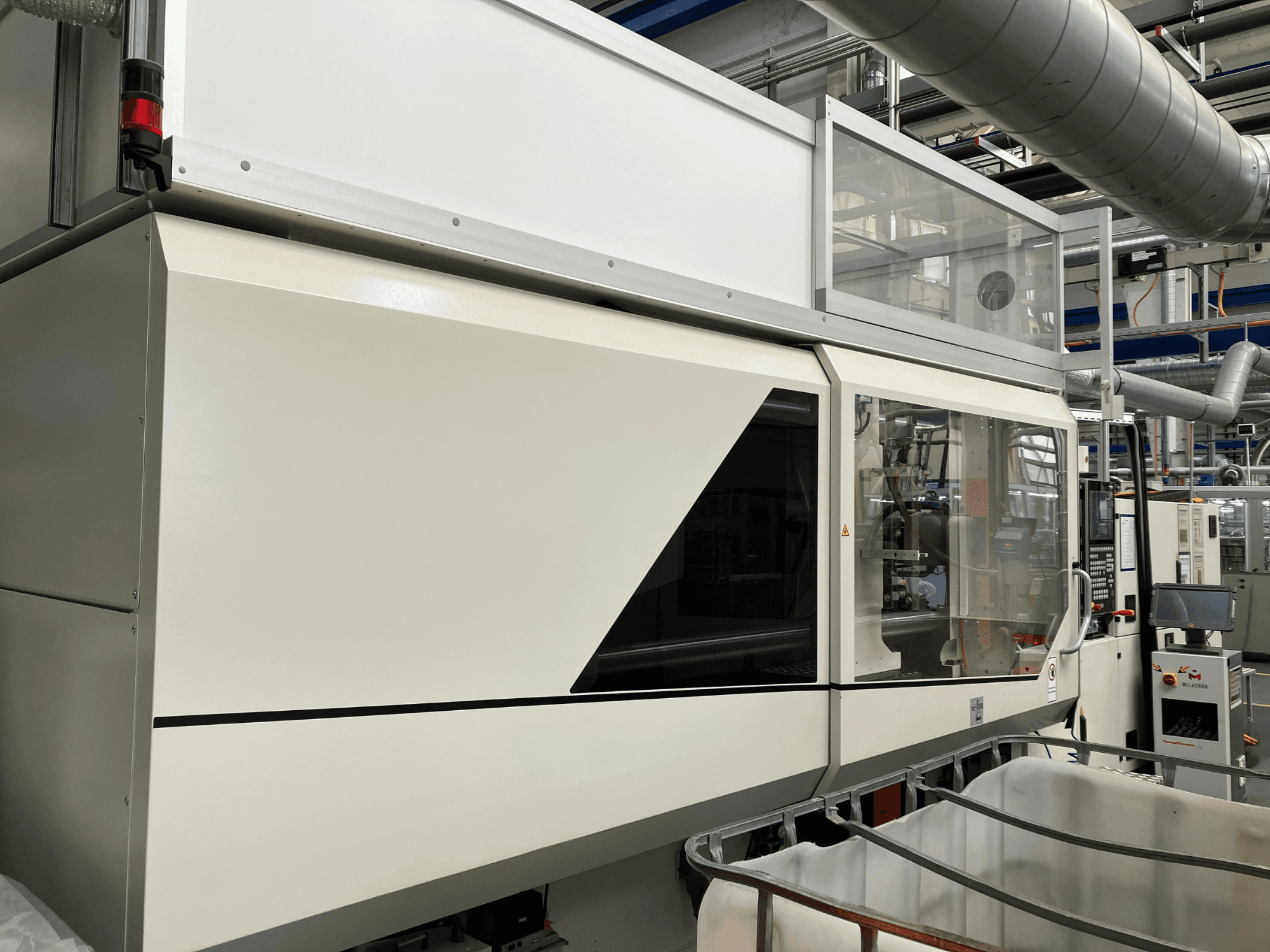 Tööstusmasina esivaade, millel on elegantne valge disain, ekraanipaneel ja klaasist osa komponentide nähtavuse tagamiseks.