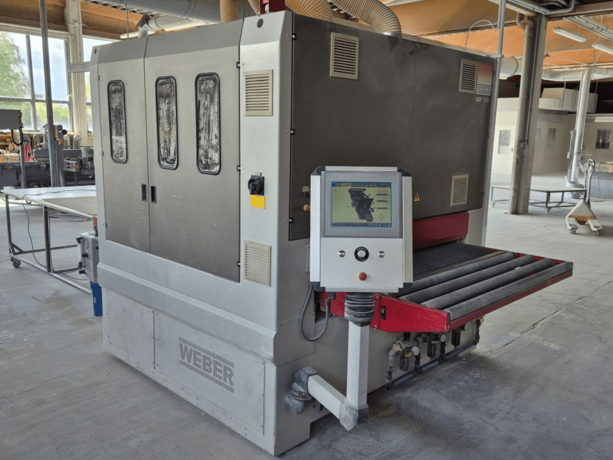 WEBER KSF-3-1350 lintlihvpinker, külgvaates on näha juhtimisseadmed, elektripaneel ja lihvimiskonveier. Tööstuslik seade koos masinatega nähtav.