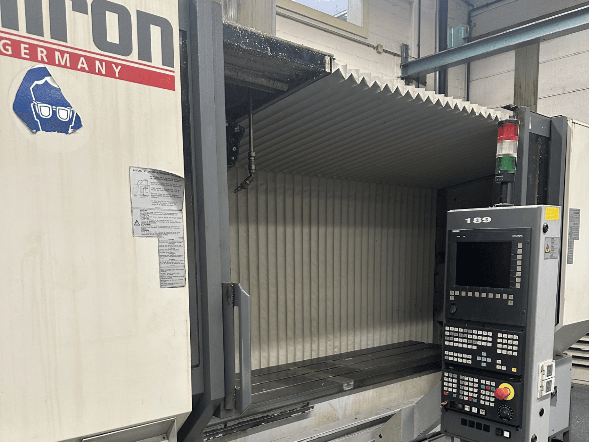 Alt tekst: Hermle CNC-pingi esivaade, millel on juhtpaneel, millel on nupud ja ekraan ning avatud tööala.