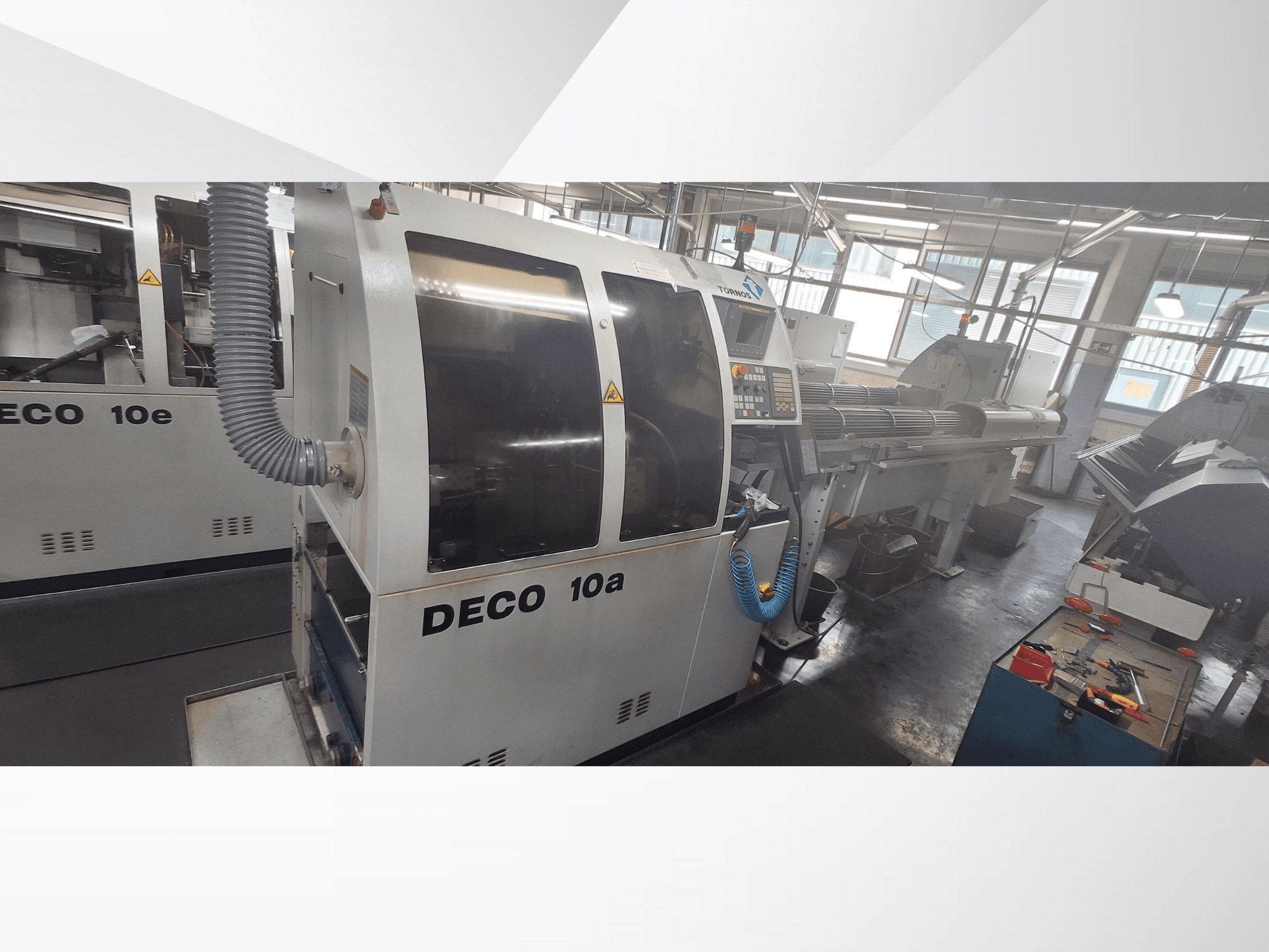 DECO 10a CNC-tööpink töökojas, kus on näha esiosa, juhtpaneel ja väljalaskesüsteem. Omadused: tugev konstruktsioon ja täppistööriistad.
