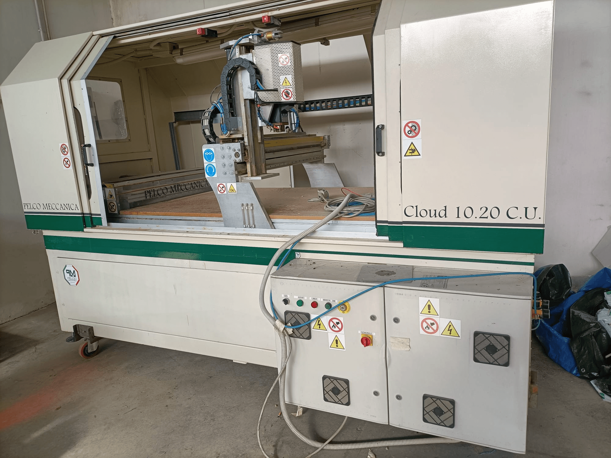CNC-freesur MECCANICA CLOUD 10.20 C.U., esiplaanil on juhtpaneel ja tööruum, nähtavad ohutussildid ja voolikud.