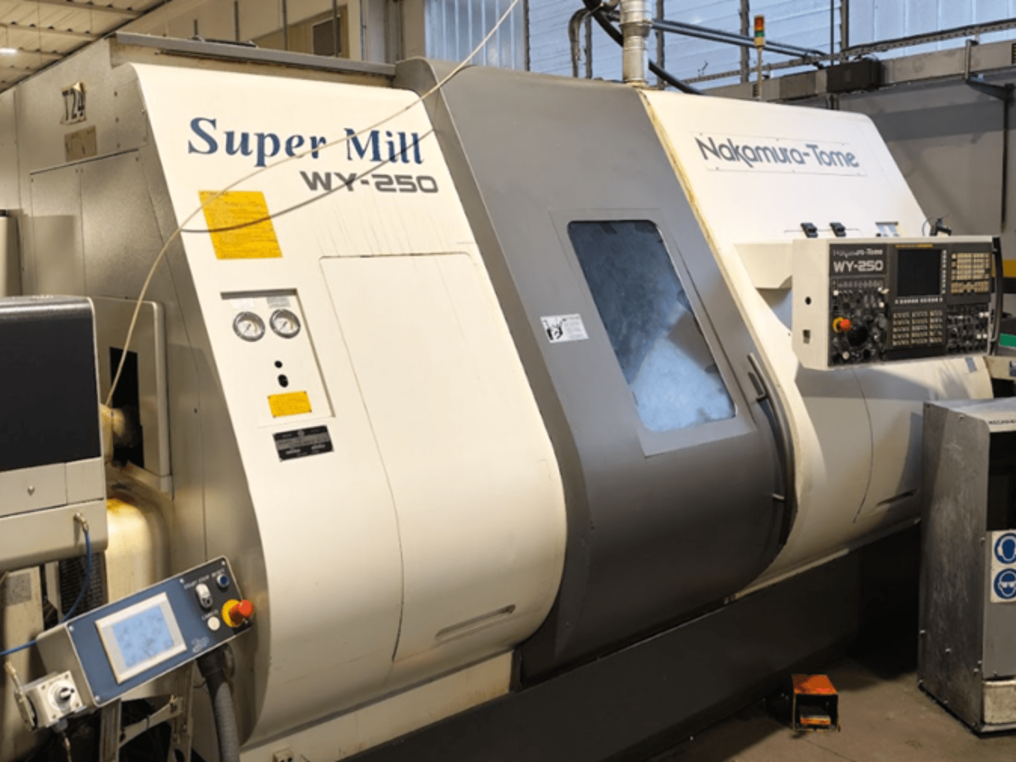 Horisontaalne treipink NAKAMURA-TOME WY 250 esiplaanil; juhtpaneel ja näidik, millel on silt "Super Mill".
