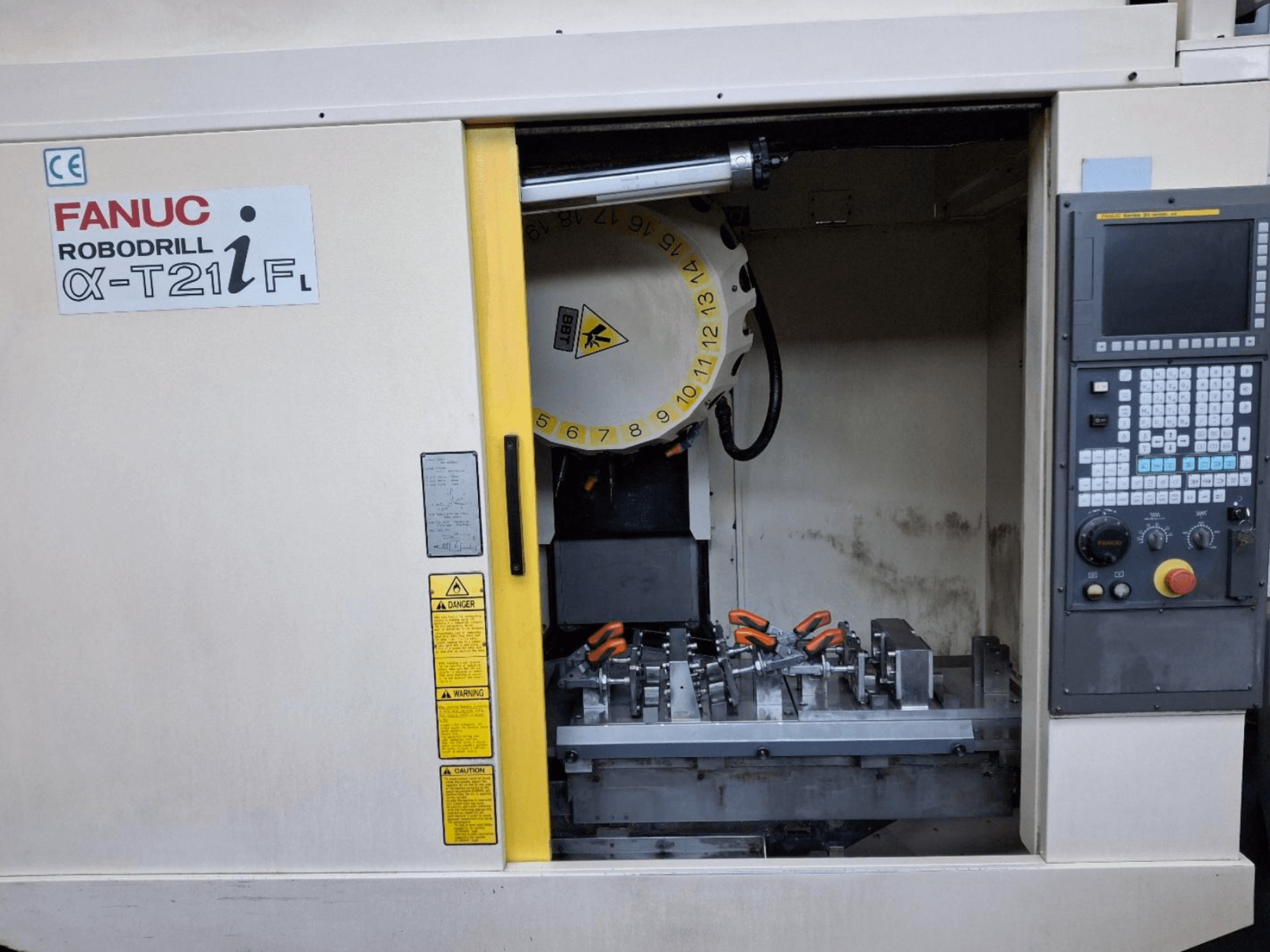 FANUC ROBODRILL α-T21iFL vertikaalne töötlemiskeskus esiplaanil, kus on näidatud tööriistad ja juhtimisseadmed masinakapis.