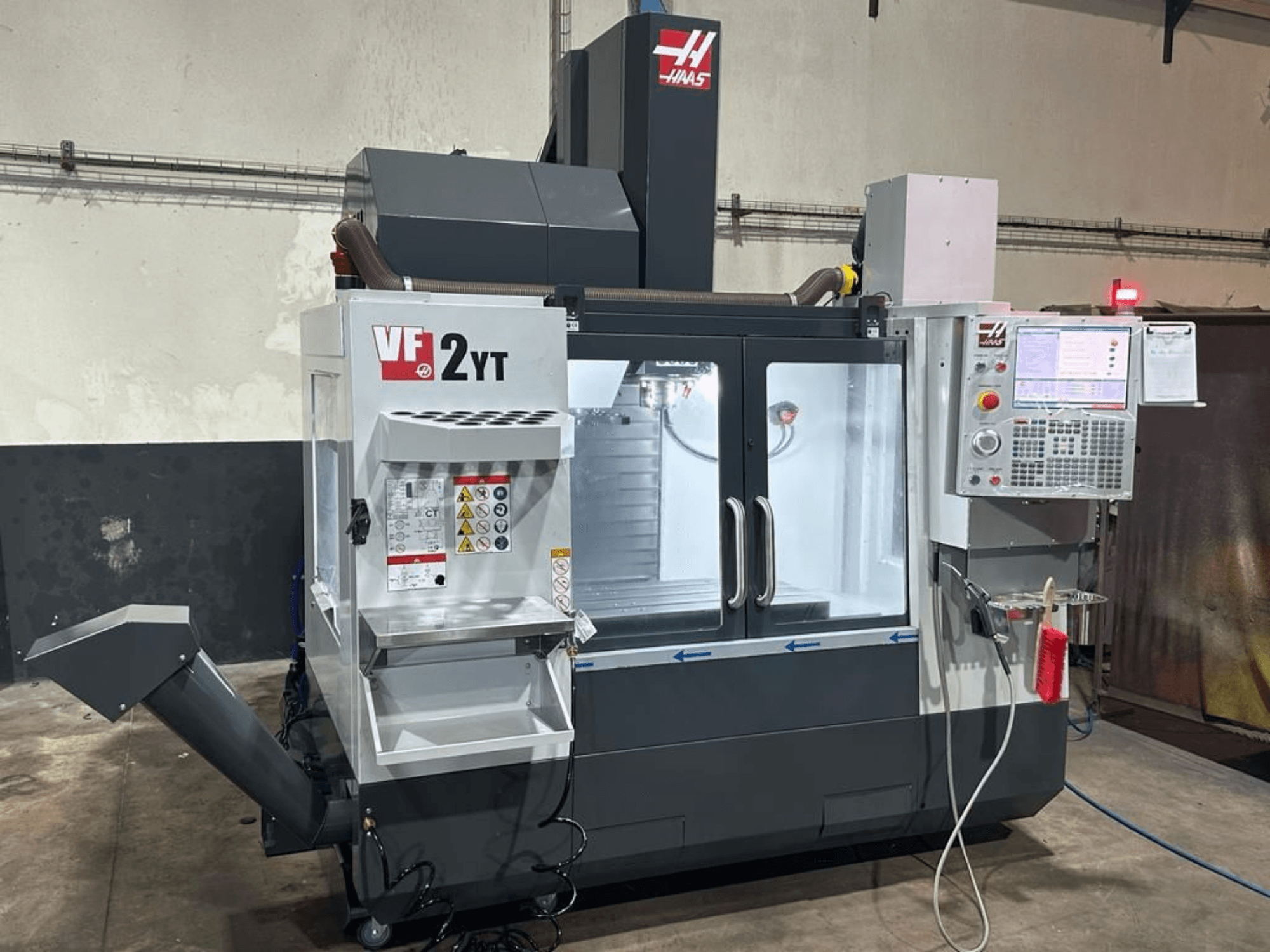 HAAS VF-2YT-EU vertikaalne töötlemiskeskus eestvaates, millel on näha juhtpaneel ja tööriistade hoiuruum.