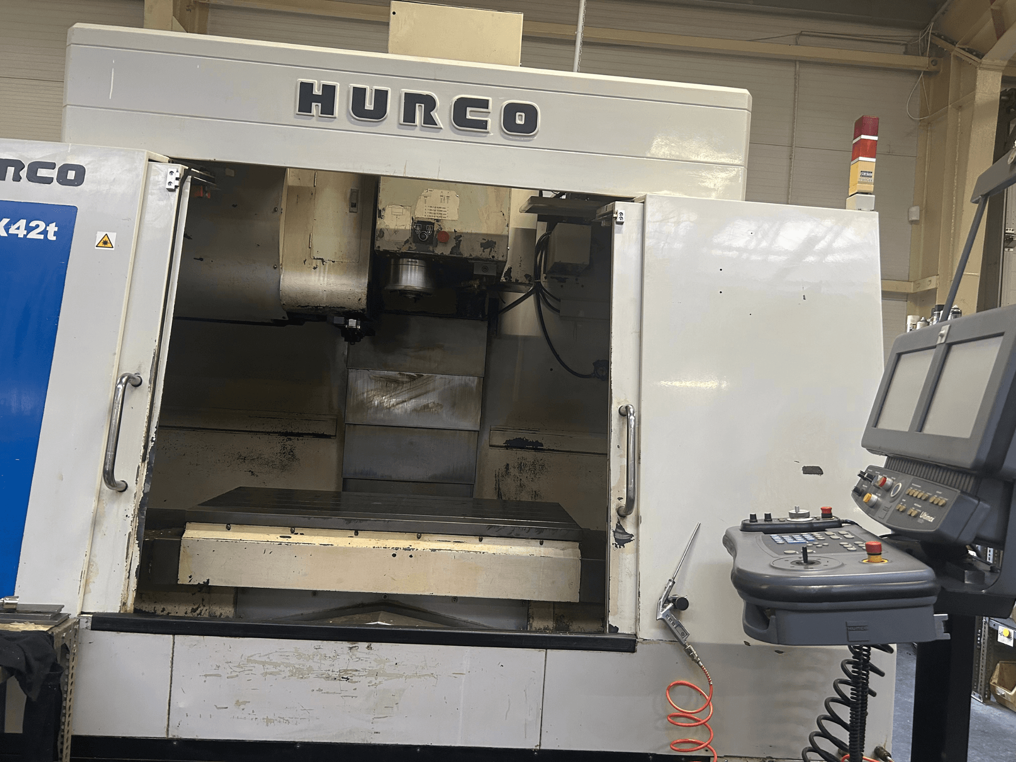 Hurco VMX42T CNC-freesping eesvaates, millel on avatud tööruum ja juhtpaneel koos nuppude ja ekraaniga.
