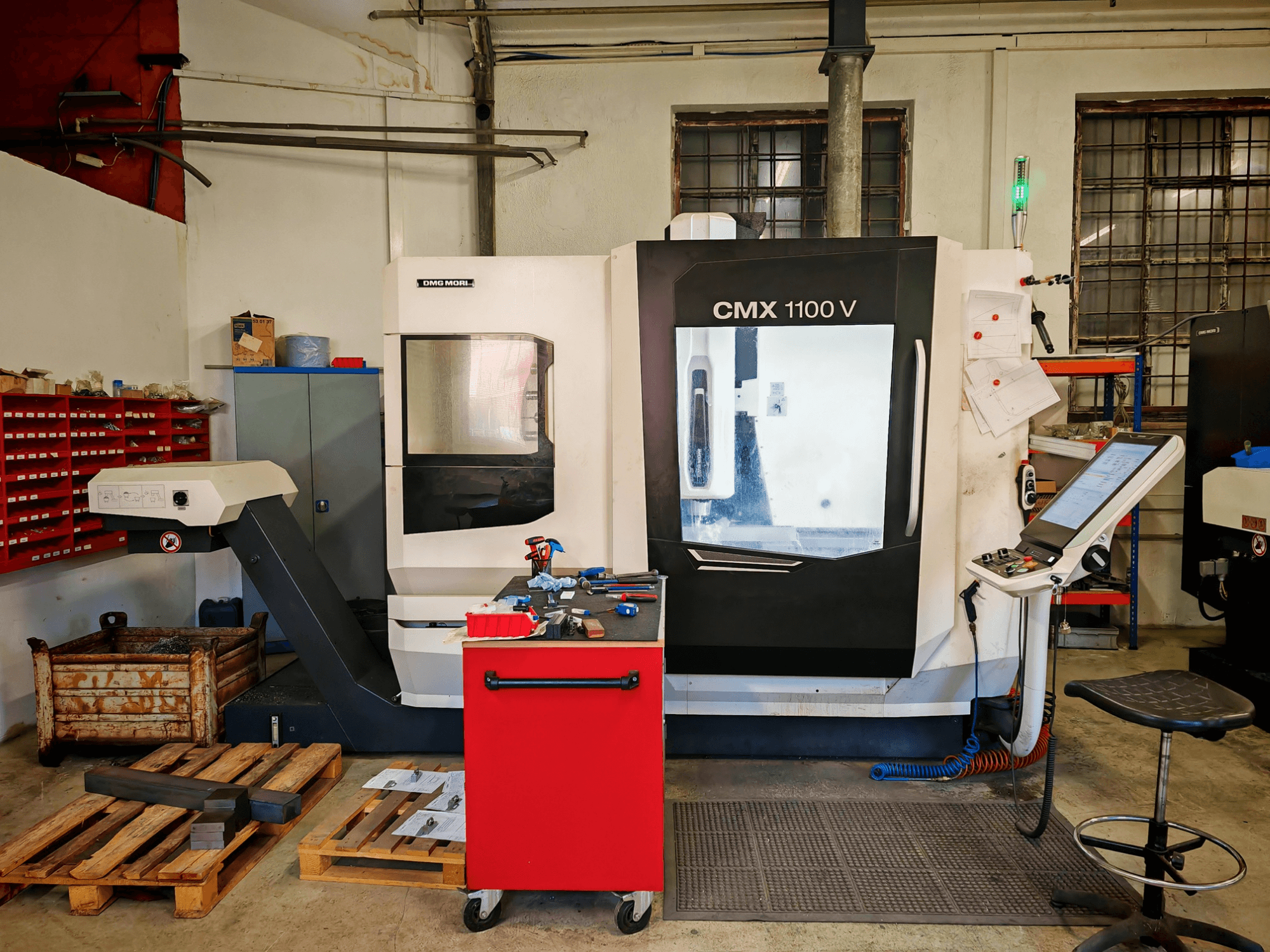 Töökojas asuv vertikaalne töötlemiskeskus DMG MORI CMX 1100 V, vaade eest, millel on näha juhtpaneel ja ümbritsevad tööriistad.